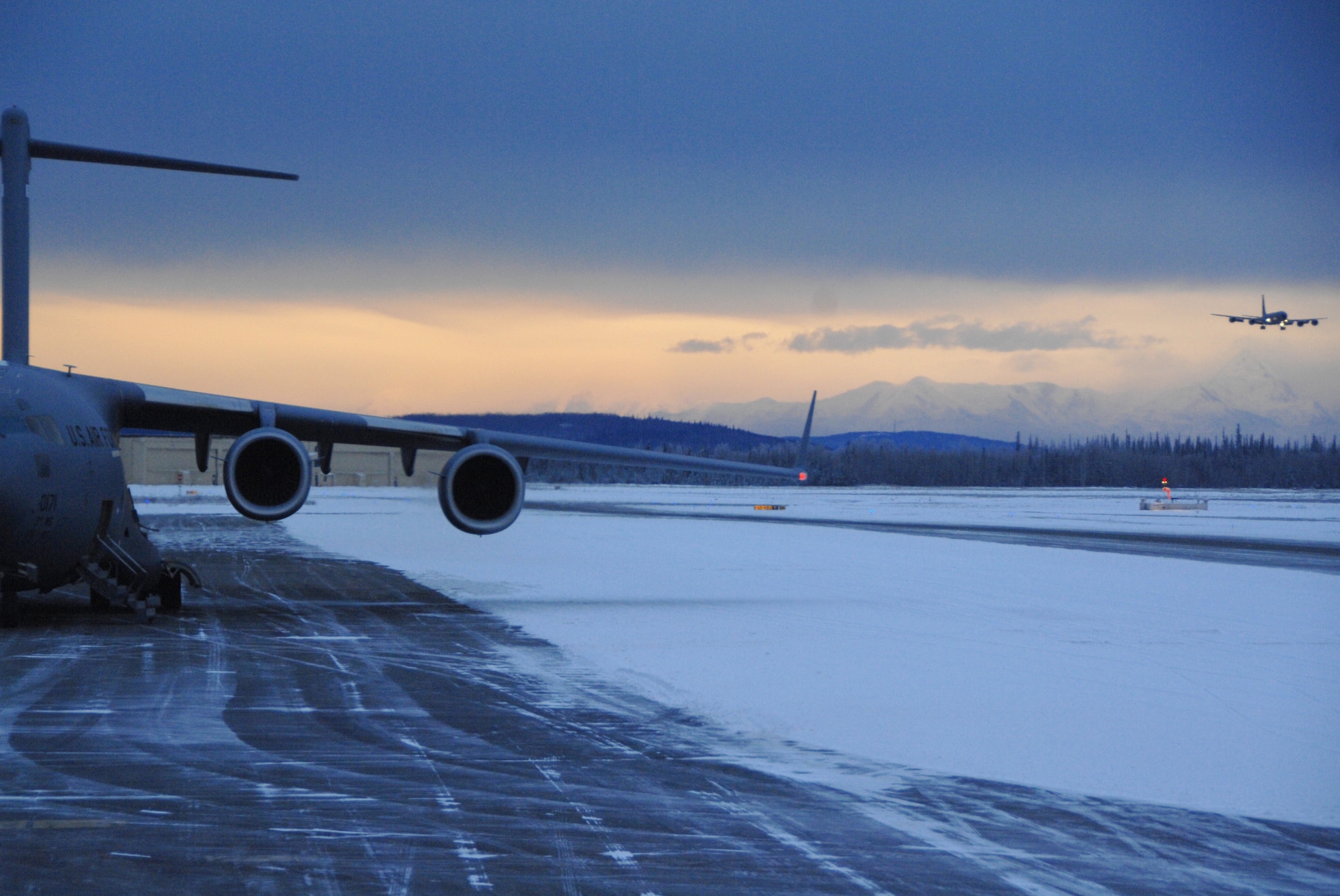 EIELSON AIR FORCE BASE, Alaska -- A C-17 sits on the Eielson flight line as a KC-135 approaches for landing Dec. 10 2007. Due to the arctic conditions and the continuous snow fall during Alaska?s extended winters, Eielson maintainers are on constant standby to assure all aircraft are ready for take-off at moment?s notice.  (U.S. Air Force photo by Airman 1st Class Christopher Griffin)