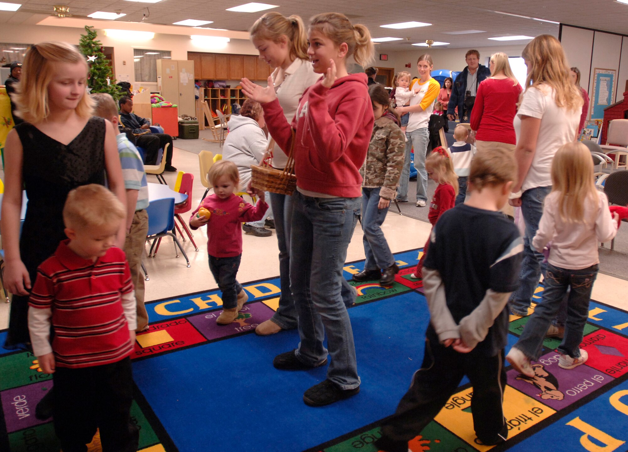 MCCONNELL AIR FORCE BASE, Kan. -- Madison Stephens and Megan Reece, center, lead a group of children in a game and hand out prizes to winners during the Hearts Apart program at the children’s playgroup building Dec. 8.  Madison and Megan spend the afternoon playing games with the children, cleaning and serving food to the families.  (Photo by Airman 1st Class Maria Ruiz)