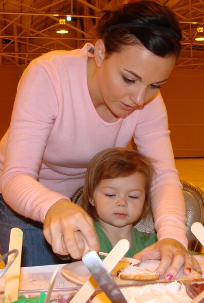 Danielle Vest helps her daughter, Kate, 1, decorate a holiday sugar cookie during "Breakfast with Santa" Dec. 8 at Hangar 170. More than 350 children and parents attended the holiday event. (U.S. Air Force photo by Tech. Sgt. Mary Davis)
