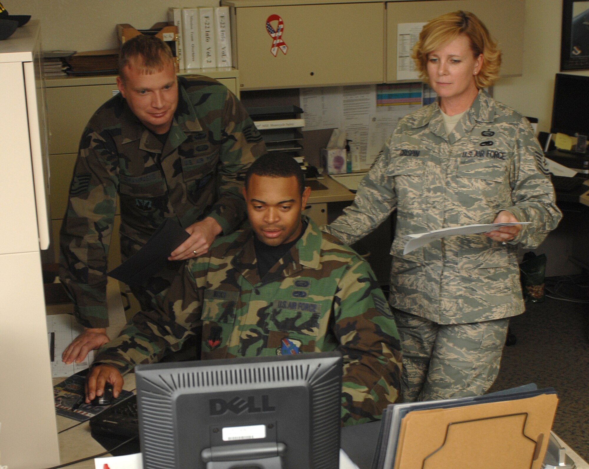 Staff Sgt. Samuel Wicks (center), and Tech. Sgts. Eric Champagne (left) and Patsy Crispin (right), 99th Mission Support Squadron manpower and organization analysts, review and discuss an organizational change request. Efforts such as these contributed the 99 MSS/MOF receiving the Air Force-level Award for Professional Excellence Flight of the Year. (U.S. Photo by Senior Airman Nadine Y. Barclay)