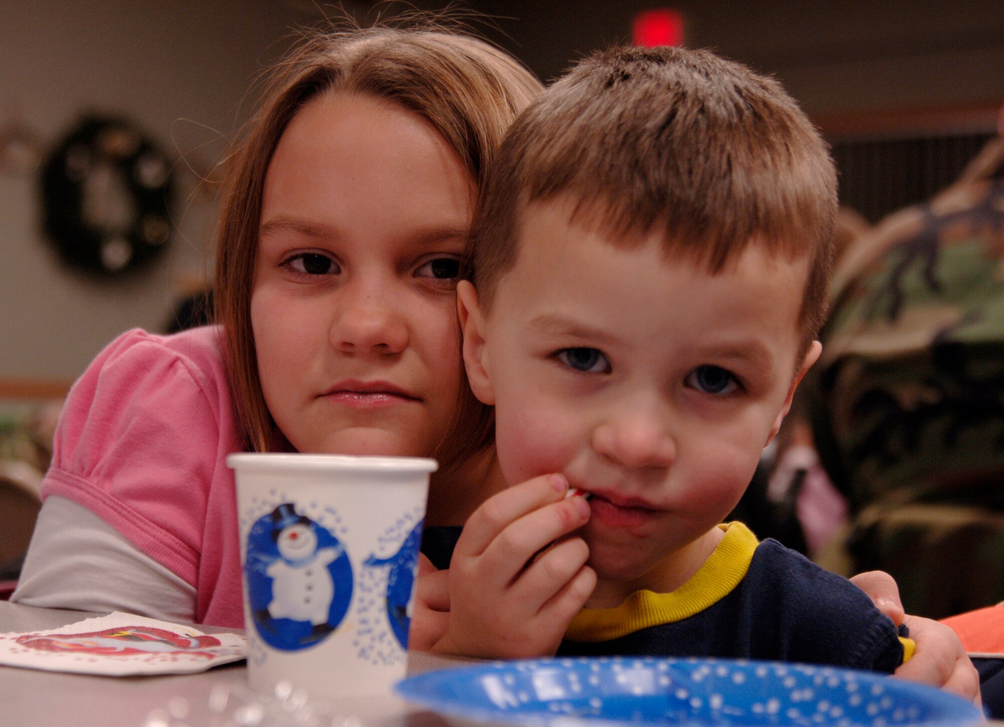 MCCONNELL AIR FORCE BASE, Kan. -- Allyson and Trenton McDonald drink hot chocolate and eat treats at the holiday tree lighting reception in the Chapel annex on Dec. 7. The reception had hot chocolate, apple cider, cookies, cupcakes, nuts and a variety of chocolate treats for holiday tree lighting ceremony participants.  (Photo by Airman 1st Class Maria Ruiz)