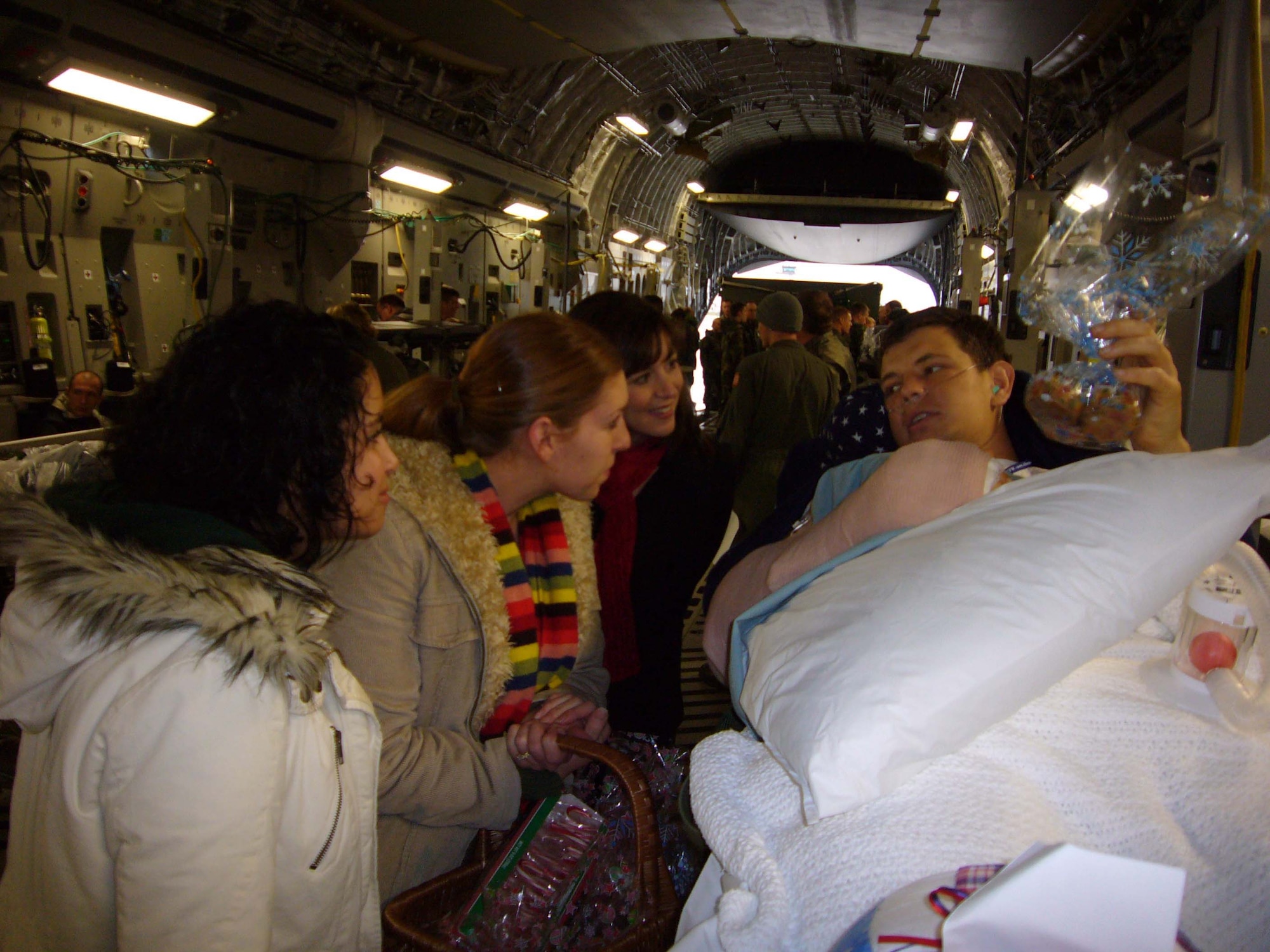 Paige Norris-Miller (left), Katie Jensen and Amy Smith, 37th Airlift Squadron bluetail spouses, deliver home-baked cookies to Tech. Sgt. Adam Popp Dec. 11 on board a C-17 Globemaster at Ramstein. (U.S. Air Force photo by Capt. Erin Dorrance)