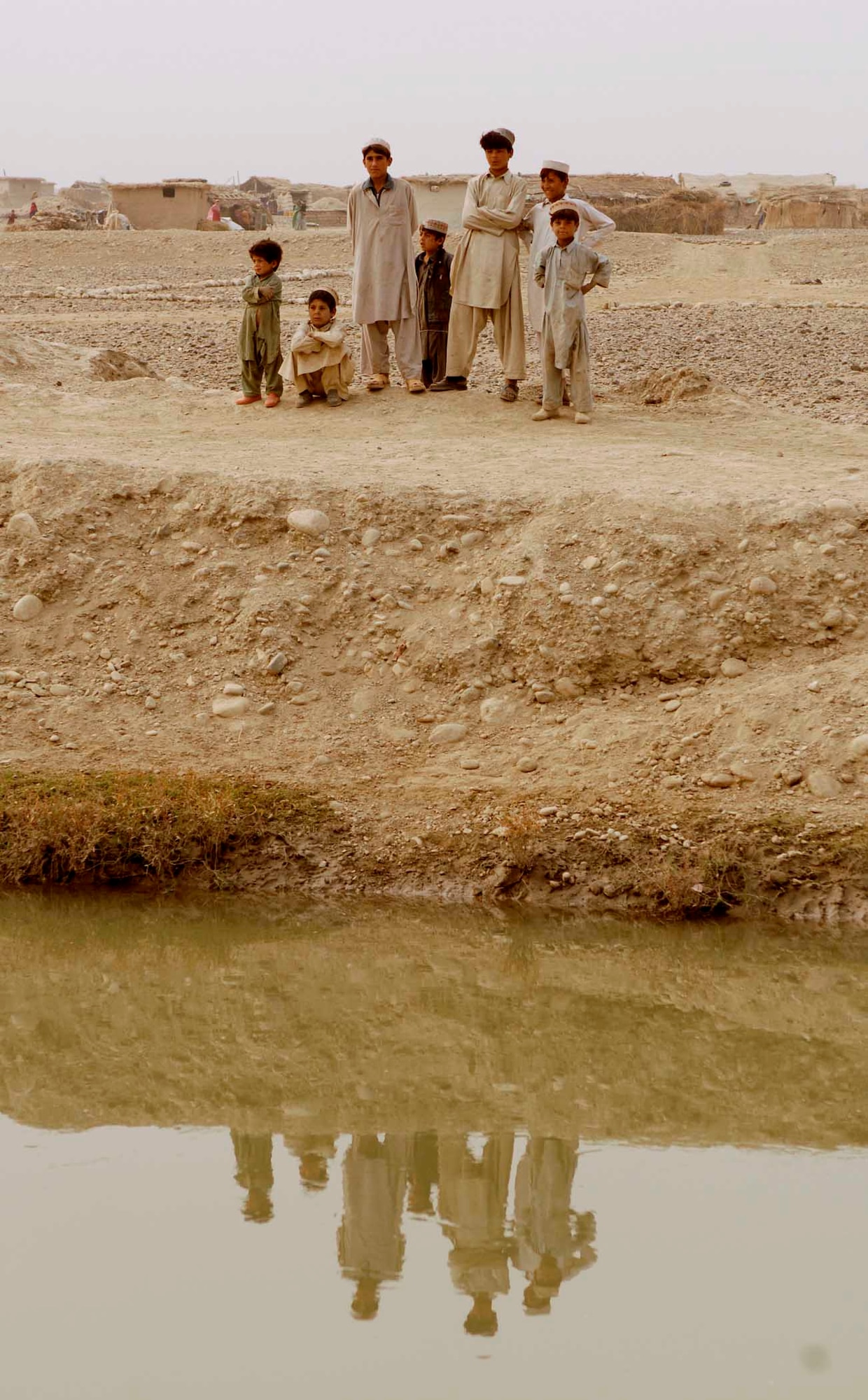 NANGARHAR PROVINCE, Afghanistan - A group of Afghan children watch the Nangarhar Provincial Reconstruction Team as they perform a canal assessment on Nov. 10, 2007.  The Nangarhar PRT is a joint team of Airman, Soldiers, and representatives from the U.S. Department of State, the U.S. Agency for International Development, and the U.S. Department of Agriculture.  The team is responsible for helping the Government of the Islamic Republic of Afghanistan improve security, governance and promote reconstruction in Nangarhar Province.  The PRT assesses community needs and then builds schools, government centers, roads, medical capability and basic infrastructure throughout the province; they also personally mentor Afghan government officials and security forces. (U.S. Air Force photo by Staff Sgt. Joshua T. Jasper)  (Released)