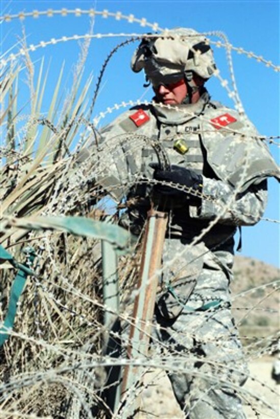 U.S. Army Spc. Jerry Thompson unhooks concertina wire at a border-crossing road to use it for a restructured traffic control point in the eastern Khowst province of Afghanistan on Nov. 17, 2007.  