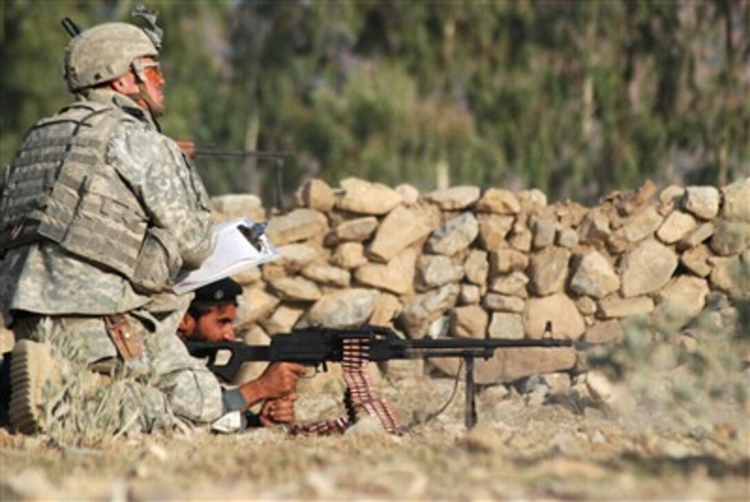 U.S. Army Sgt. Jeremiah K. Stafford watches as an Afghan Border Policeman fires a PKM machine gun during marksmanship training in the eastern Khowst province of Afghanistan on Nov. 19, 2007.  