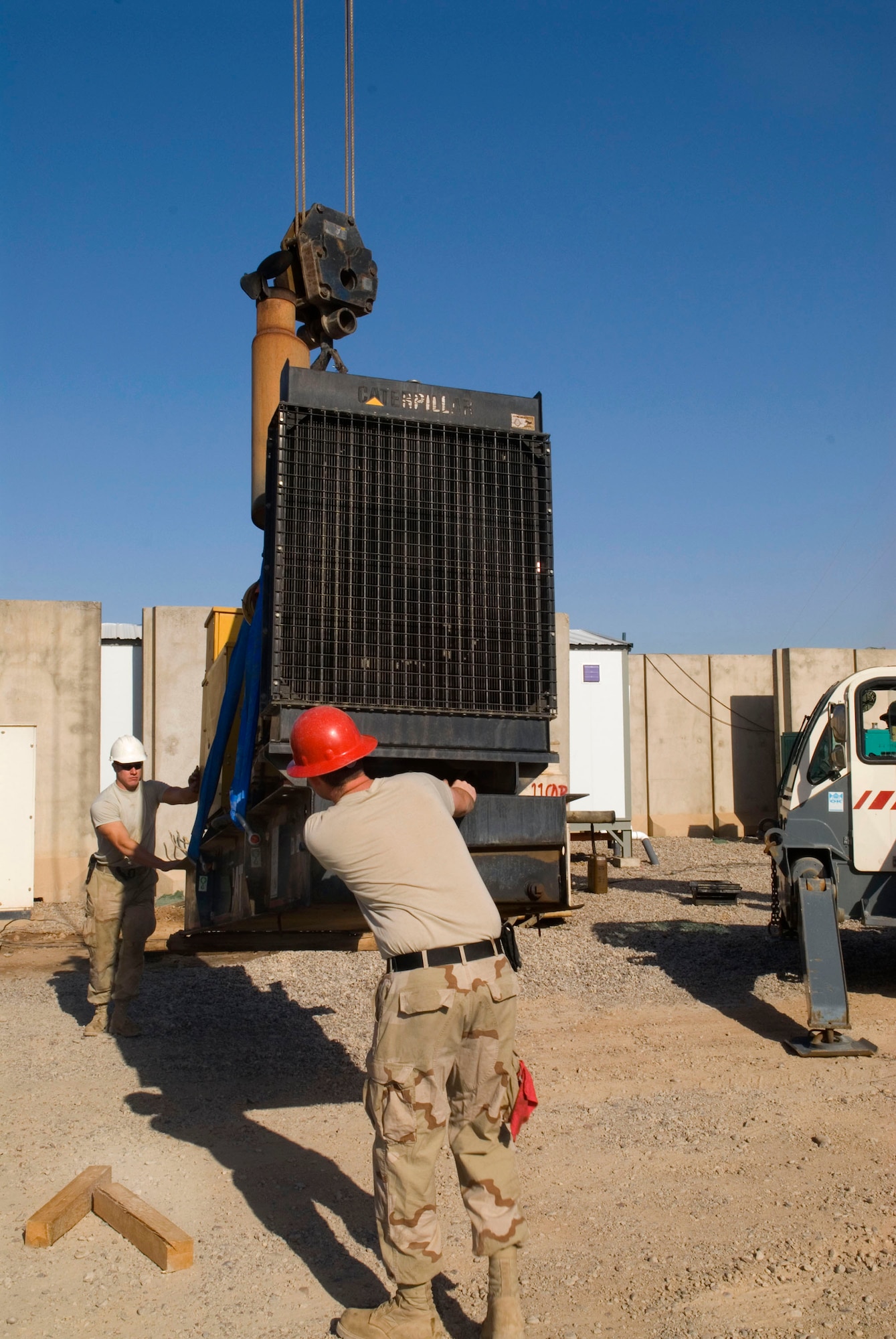 Senior Airmen Charles Hernandez and Paul Edwards guide a generator into position as it is lowered by a crane Dec. 8 at Balad Air Base, Iraq. Power production members replace generators as necessary to ensure facilities receive sufficiant power. Airman Hernandez is deployed from Kadena Air Base, Japan, and Airman Edwards is deployed from the Missouri Air National Guard. The Airmen are with the 332nd Expeditionary Civil Engineer Squadron. (U.S. Air Force photo/Staff Sgt. Joshua Garcia)