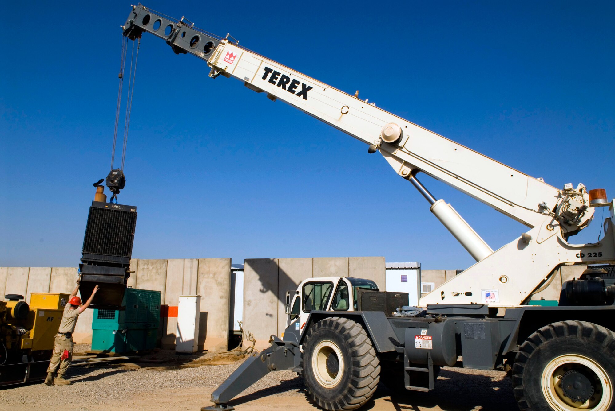 Members of the 332nd Expeditionary Civil Engineer Squadron lower a generator into position Dec. 8 at Balad Air Base, Iraq. It takes orchastrated teamwork between the power production and heavy equipment shops to ensure mission completion when generators are switched out. (U.S. Air Force photo/Staff Sgt. Joshua Garcia)