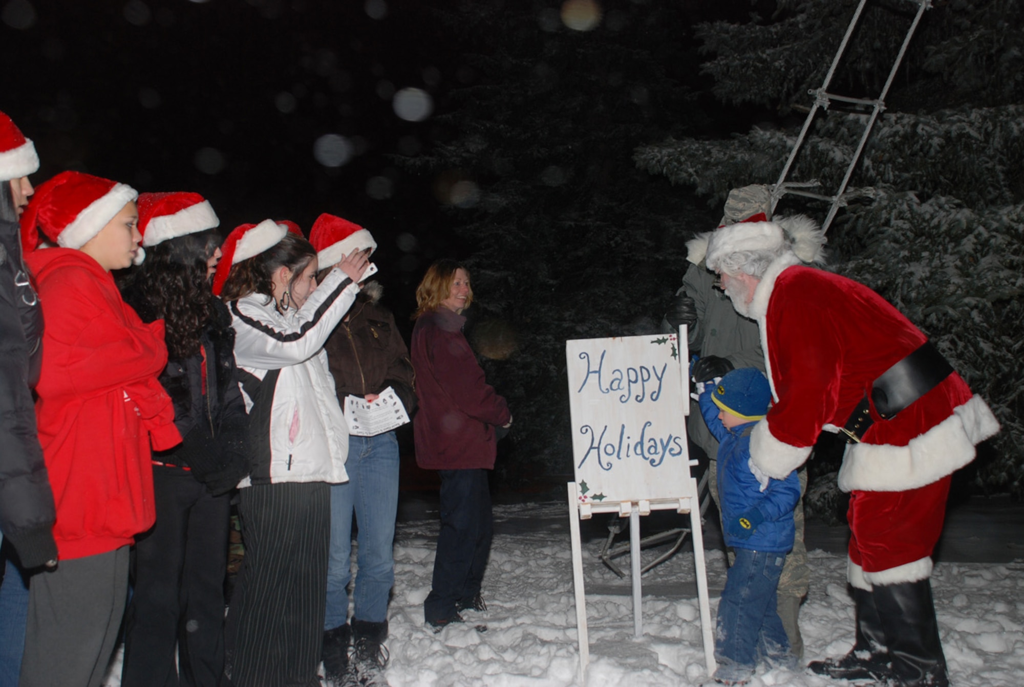 Santa Claus, as portrayed by Mike Woods from the 90th Space Wing Safety office, guides a child around the wing tree during the 90th SW annual tree lighting ceremony Dec. 7. The majority of the ceremony was held in Fall Hall Community Center due to the winter weather (U.S. Air Force photo by Airman 1st Class Alex Martinez).