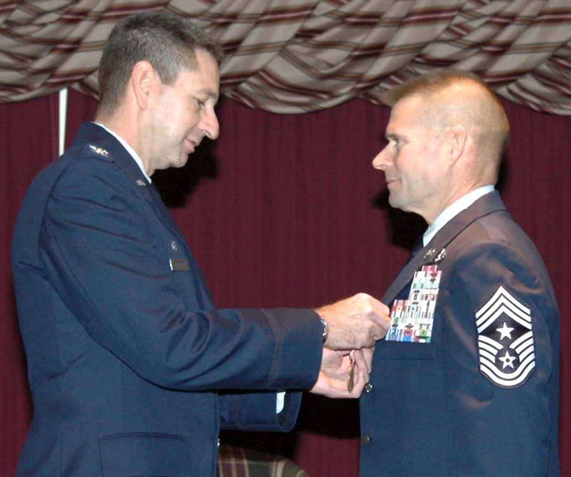 Col. Mark Correll, 72nd Air Base Wing and Tinker installation commander, pins a Meritorious Service Medal onto Chief Master Sgt. Phillip Cherry’s lapel for his major accomplishments while stationed at Tinker. The 72nd ABW command chief master sergeant retired Dec. 10 after a 29-year career. (Air Force photo by Ralph Monson)