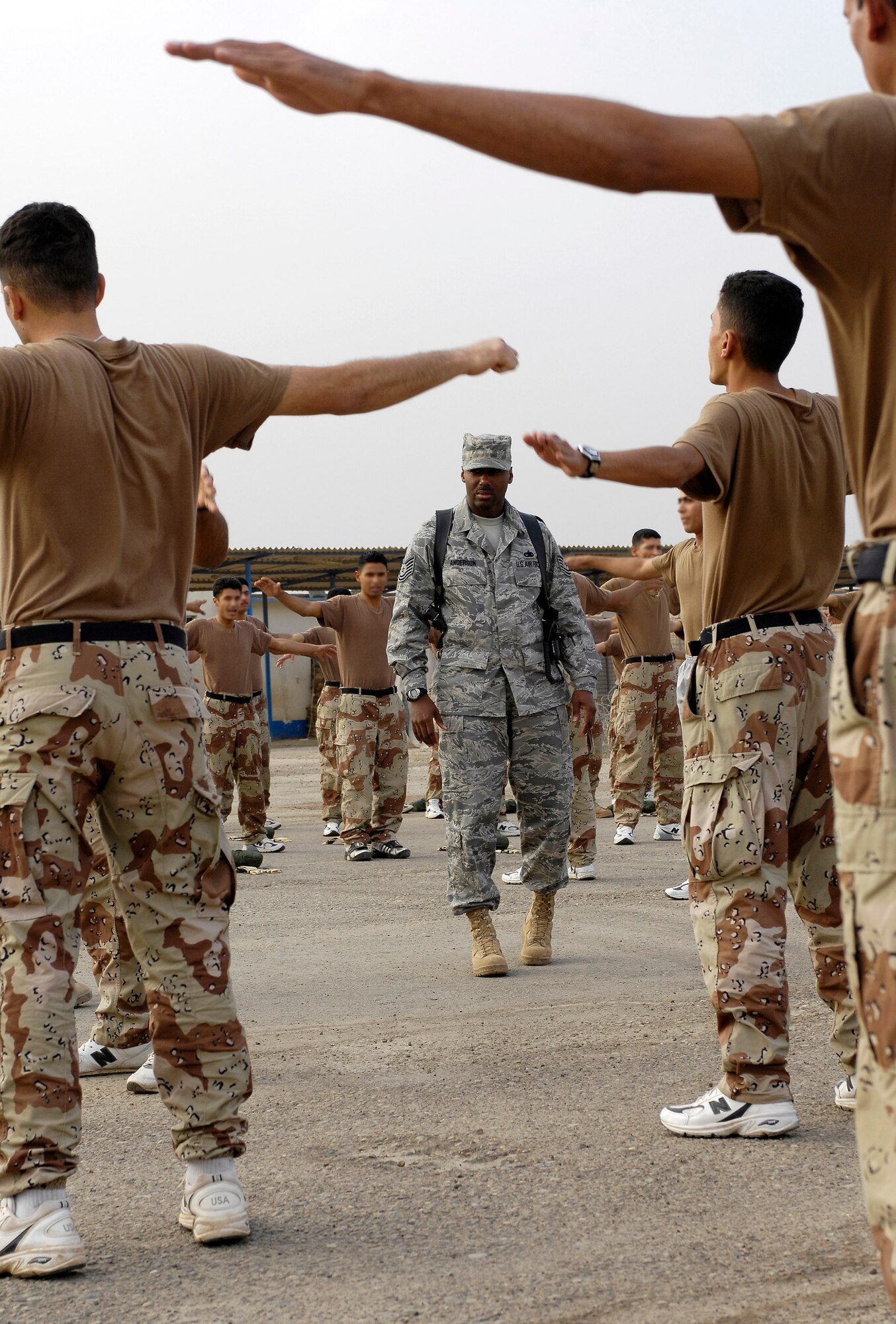 Tech. Sgt. Lamar Anderson observes Iraqi air force warrant officer trainees warming up before a 30 minute self-paced run. Sergeant Anderson is a military training instructor from Lackland Air Force Base, Texas, and is assigned to the 370th Expeditionary Training Squadron at Taji Air Base, Iraq. The Lackland AFB MTIs are helping to mold Iraq's future leaders. (U.S. Air Force photo/Staff Sgt. Brian Ferguson) 
