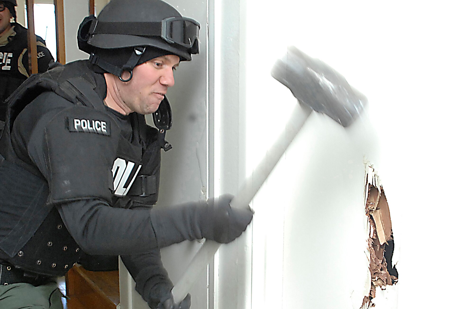 CANNON AIR FORCE BASE, N.M. -- Clovis, N.M. police officer Tim Marshall takes out a door after entering an abandoned house here during joint training with 27th Special Operations Security Forces Squadron Airmen. The two organizations have a mutual support aggreement for crisis situations on base. (Air Force photo by Airman 1st Class Erik Cardenas)