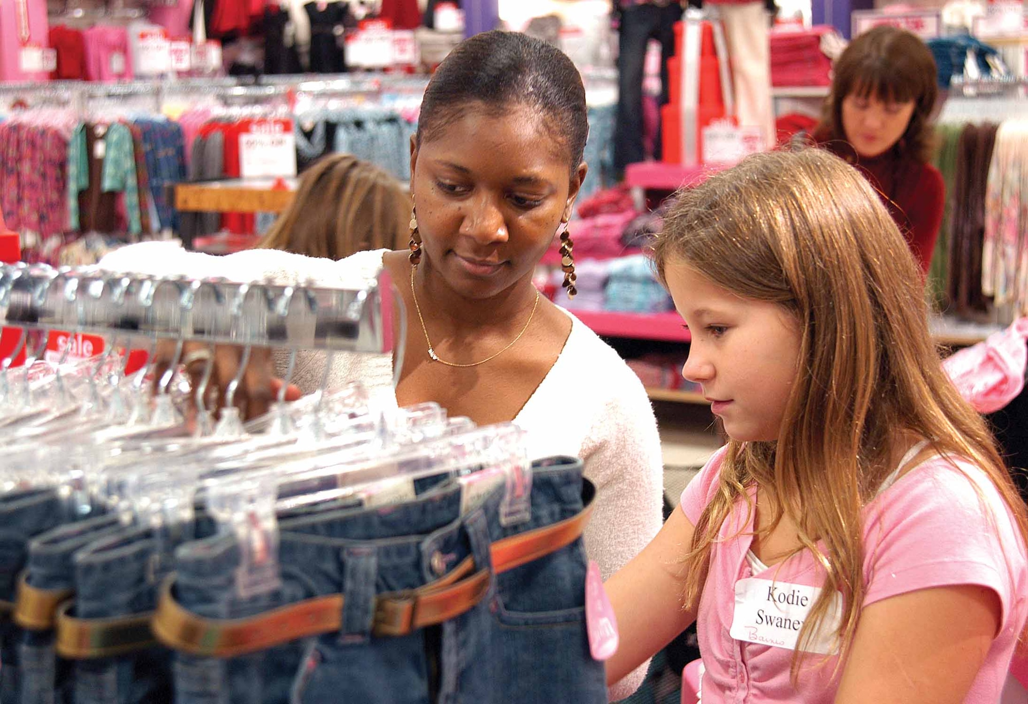 Christie Sanders and 10-year-old Kodie Swaney hunt for a size during the 727th Aircraft Sustainment Group’s annual holiday event to provide new clothes for area students.  A first-time volunteer with the program, Ms. Sanders’ eyes welled as she described the girl’s excitement and appreciation to get clothes that included new shoes and a warm coat. (Air Force photo by Margo Wright) 