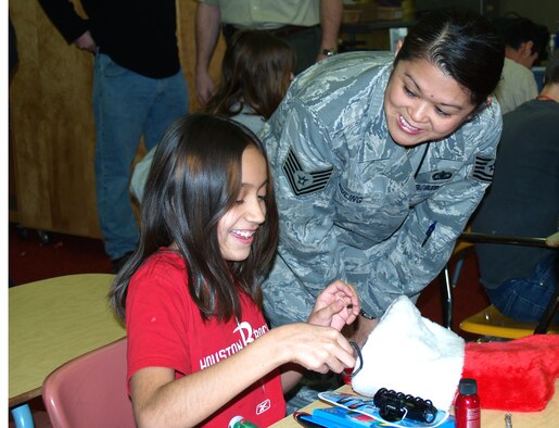 Tech. Sgt. Kanya Huling, of the 67th Aerial Port Squadron, talks to a Mound Fort Middle School student as she sifts through the goodies in her stocking. Continuing an 18-year tradition, members of the 67th APS hosted a Christmas party for special-needs students at the Ogden school Dec. 12. Chief Master Sgt. David Sill played Santa, giving each child a large bag of gifts. The 67th APS raises funds throughout the year to buys gifts for the children at Christmastime. (U.S. Air Force Photo/Bryan Magaña)