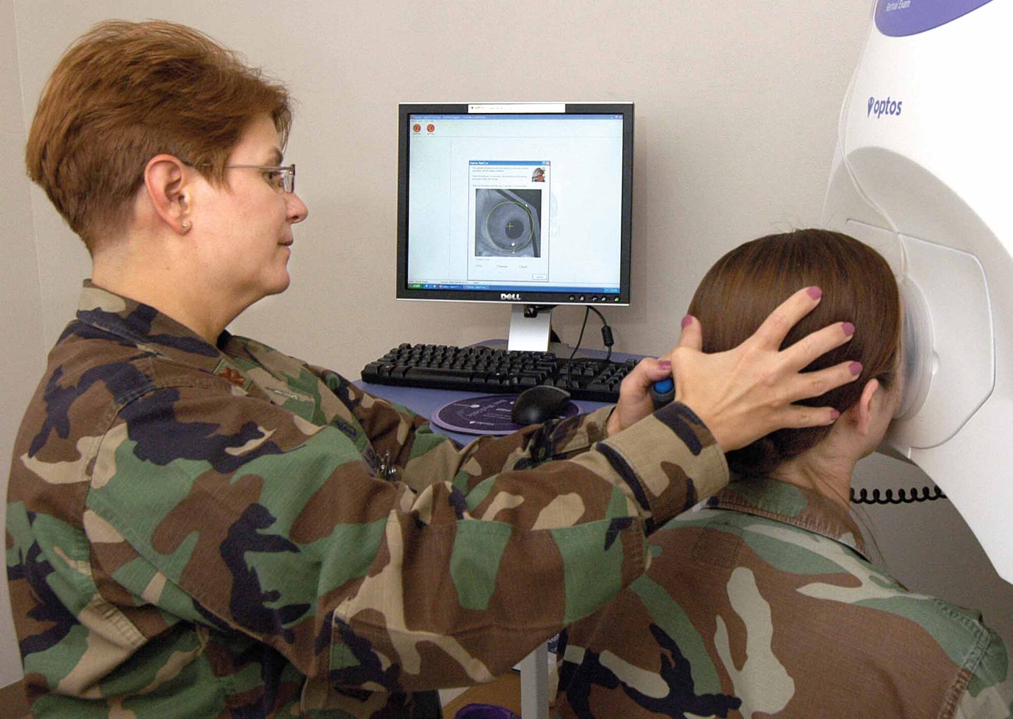 Dr. (Maj.) Judy Manno shows how a 72nd Medical Group Optometry Clinic patient is positioned to give the best retinal mapping with the new ophthalmoscope. The flight commander and optometrist praised the equipment which gives a 200-degree view of the interior of the eye with no dilation necessary.  (Air Force photos by Margo Wright)