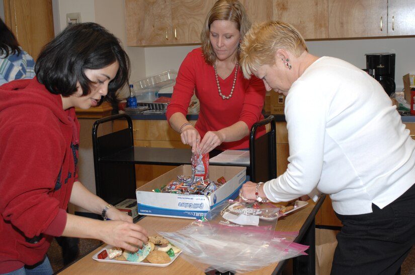 LANGLEY AIR FORCE BASE, Va. -- Nancy Gray (left) wife of Maj. Darren Gray, Kris Cole (center) cookie drive chairmen, and Libby Marks wife of retired Maj. Larry Marks put the finishing touches on cookie packages Dec. 14. The cookie packages were distributed to dormitory residence and other base personnel. (U.S. Air Force photo/Staff Sgt. April Wickes) 
