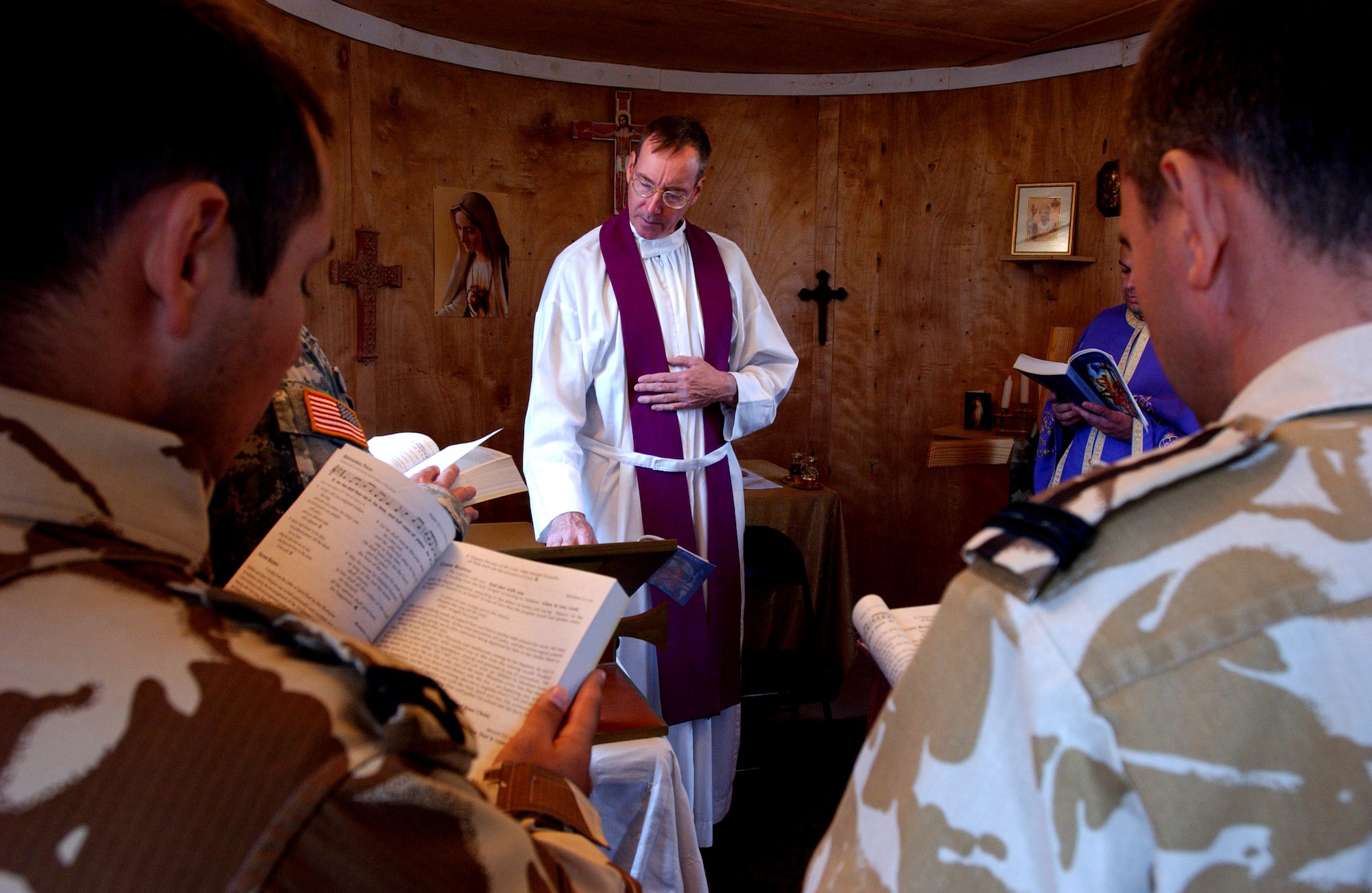Chaplain (Maj.) Timothy Hirten reads a prayer while Warrant Officer Ionut Gabriel Mittelbrun, left, and Lt. Col. Marian Popa, follow along with the reading Dec. 5 at the Romanian chapel on Ali Base, Iraq. Chaplain Hirten volunteers his time to help lead a Catholic Mass for coalition forces at the Romanian camp. The chaplain is assigned to the 407th Air Expeditionary Group Chapel and is deployed from Altus Air Force Base, Okla. Warrant Officer Mittelbrun and Colonel Popa are both assigned to the Romanian Army. (U.S. Air Force photo/Airman 1st Class Jonathan Snyder) 