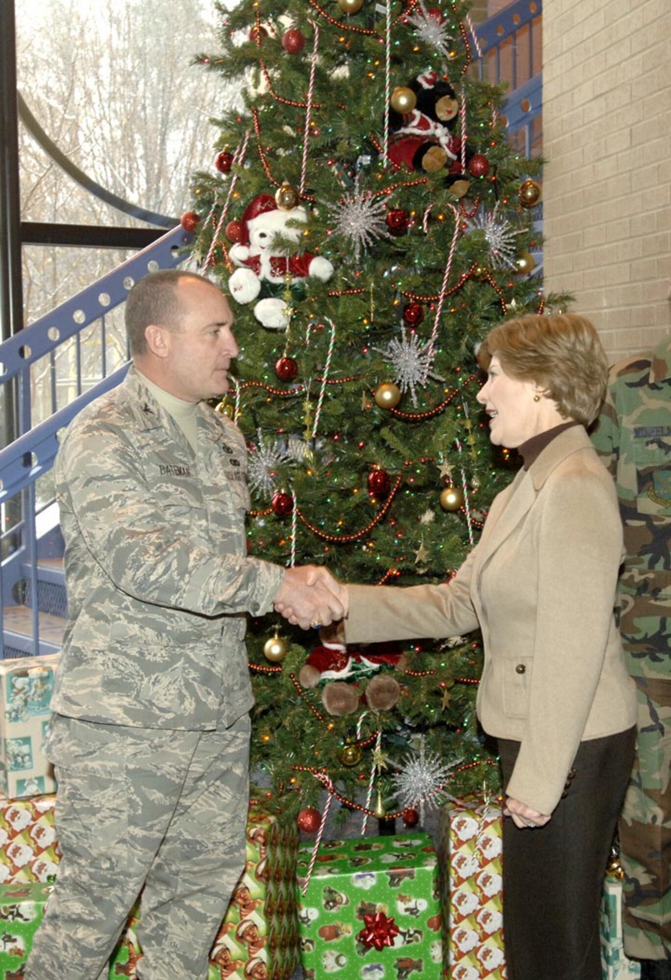 First Lady Laura Bush shakes hands with Col. Jeffery Batemen, 316th Security Forces Squadron commander in front fo the Crhsitmas tree and gifts in the Youth Center on Dec. 5. (US Air Force/TSgt Jason Edwards)