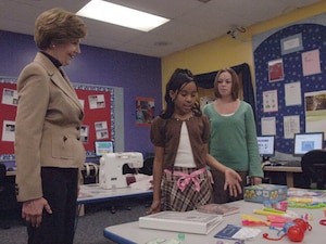 Rachel Seagraves, School Age Program assistant, observes as Taylor Rice, daughter of 1st Lt. Troy Rice, Air National Guard, shows First Lady Laura Bush the developmental tools used at the Youth Center for education and fun. Mrs. Bush made an official visit to Andrews on Dec. 5, to tour the Youth Center and to hold a panel on helping America's military youth. The panel consisted of Mrs. Bush, the Boys and Girls Club of America, the Military Child Education Coalition as well as several military members and their children. She also autographed and donated several books to the youth center for children to read, including Tuck Everlasting, by Natalie Babbit, Esperanza Rising, by Pam Munoz Ryan, and A Wrinkle In Time, by Madelin L'Engle. (US Air Force/TSgt Jason Edwards)