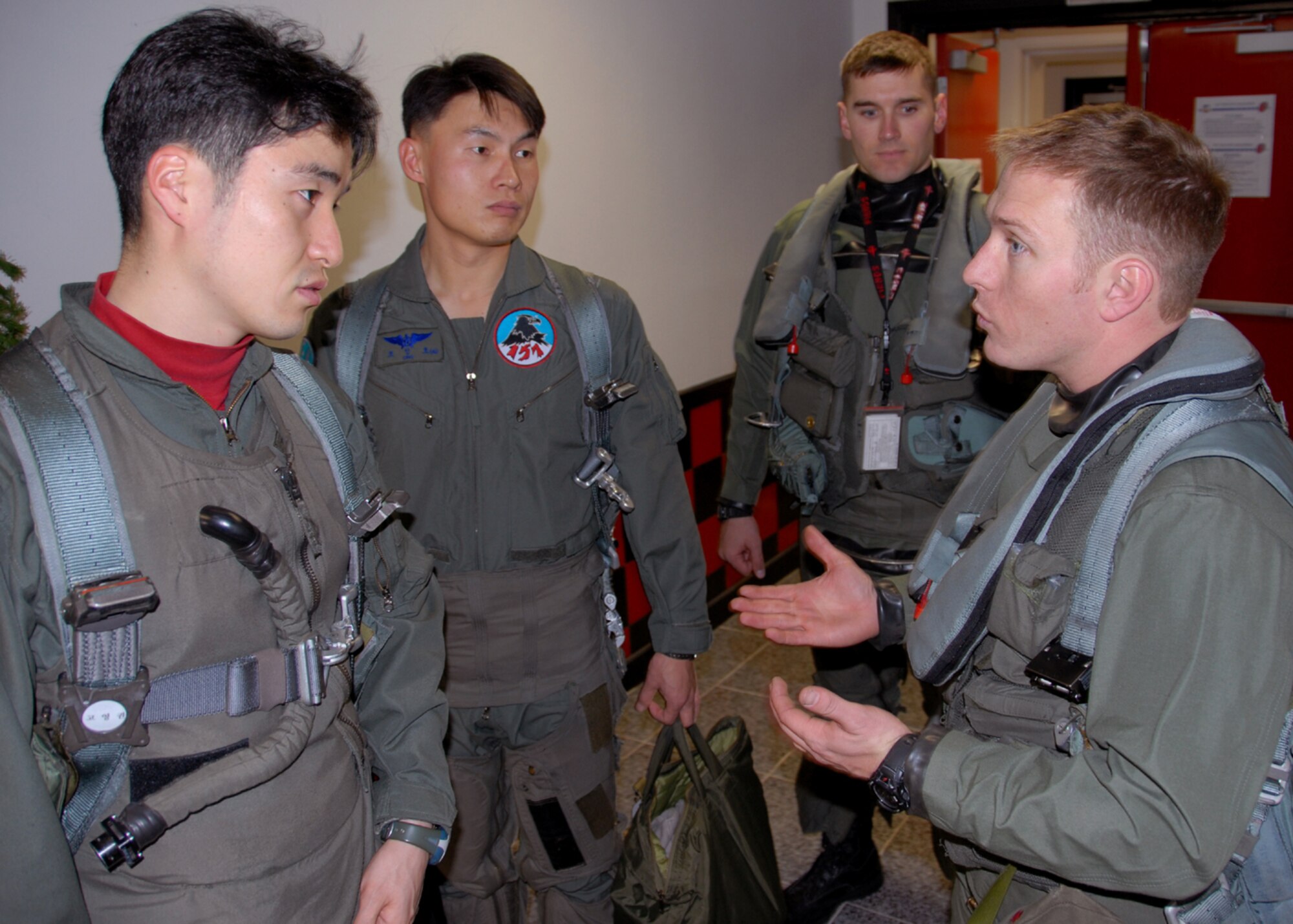 OSAN AIR BASE, Republic of Korea -- Captain Paul Davidson (right) an F-16C Fighting Falcon pilot assigned to the 36th Fighter Squadron, provides feedback after a Buddy Wing sortie with Captain Young-Kwon Ko (left) and Captain Jeong-Ho Cho (second from left) both from the 157th Tactical Fighter Squadron, Seosan Air Base, Republic of Korea Air Force, with Captain William Bolton (second from right) assigned to the 36th Fighter Squadron looking on during the Buddy Wing program 11 through 13 December.  The purpose of the Buddy Wing program is to exchange ideas, introduce tactics and improve interoperability between the U.S. and Republic of Korea Air Forces.  (U. S. Air Force photo by Senior Master Sgt Marvin Krause)