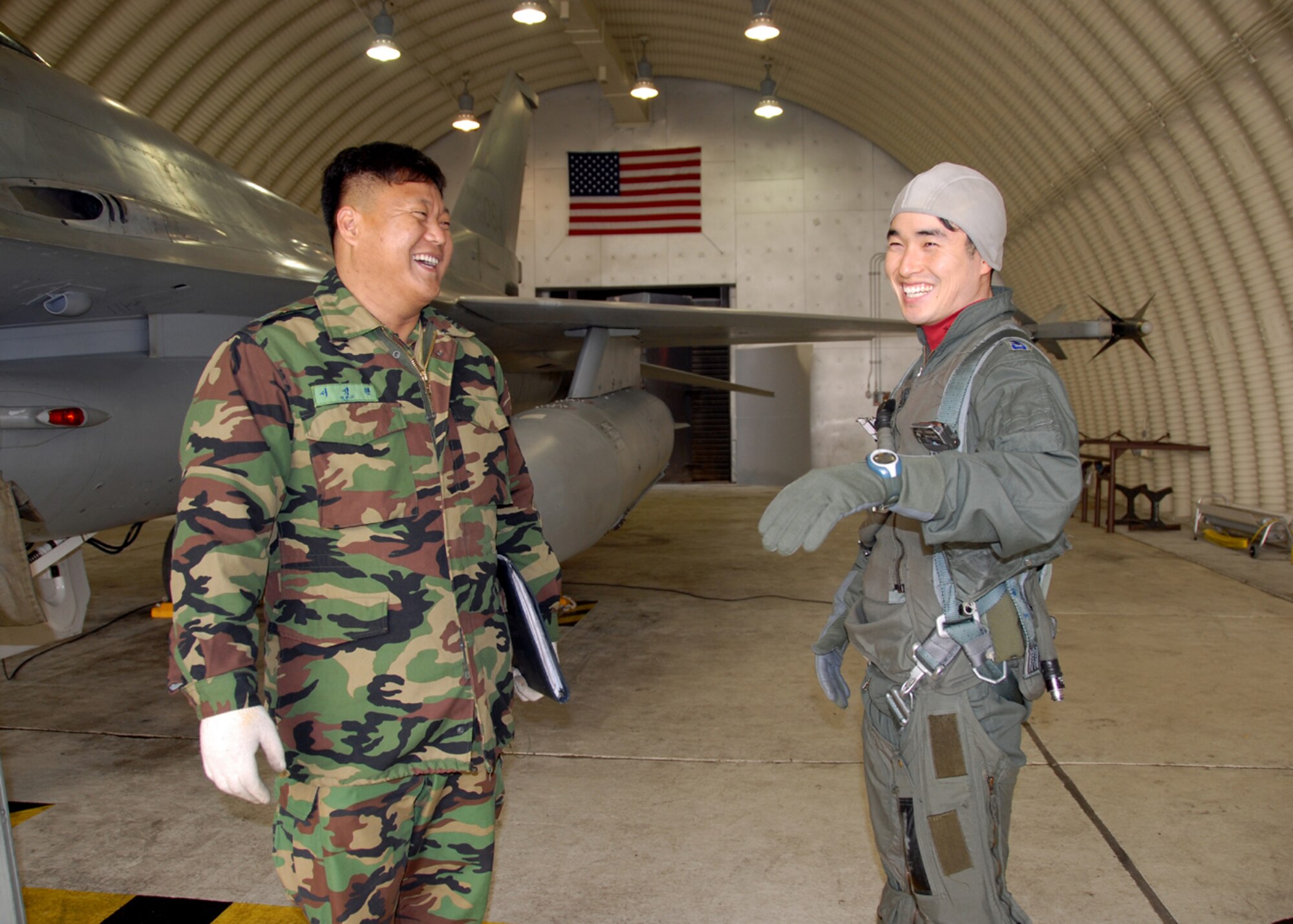 OSAN AIR BASE, Republic of Korea – Captain Young-Kwon Ko (right) a KF-16C Fighting Falcon pilot, shares a laugh with his crew chief, Master Sgt Seong Weon Seo, both assigned to the 157th Tactical Fighter Squadron, Seosan Air Base, Republic of Korea Air Force, prior to Capt Ko’s Buddy Wing sortie with U. S. Air Force pilots assigned to the 36th Fighter squadron 11 through 13 December.  The purpose of the Buddy Wing program is to exchange ideas, introduce tactics and improve interoperability between the U.S. and Republic of Korea Air Forces.  (U. S. Air Force photo by Senior Master Sgt Marvin Krause)