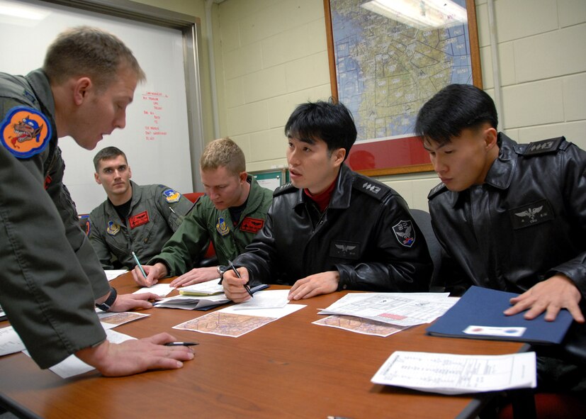OSAN AIR BASE, Republic of Korea -- Captain Paul Davidson (left) an F-16C Fighting Falcon pilot assigned to the 36th Fighter Squadron, conducts flight planning with Captain Young-Kwon Ko (center) and Captain Jeong-Ho Cho (right) from the 157th Tactical Fighter Squadron, Seosan Air Base, Republic of Korea Air Force, with Captain William Bolton (left) and Captain Chris Miller, pilots assigned to the 36th Fighter Squadron during the Buddy Wing program 11 through 13 December.  The purpose of the Buddy Wing program is to exchange ideas, introduce tactics and improve interoperability between the U.S. and Republic of Korea Air Forces.  (U. S. Air Force photo by Senior Master Sgt Marvin Krause)