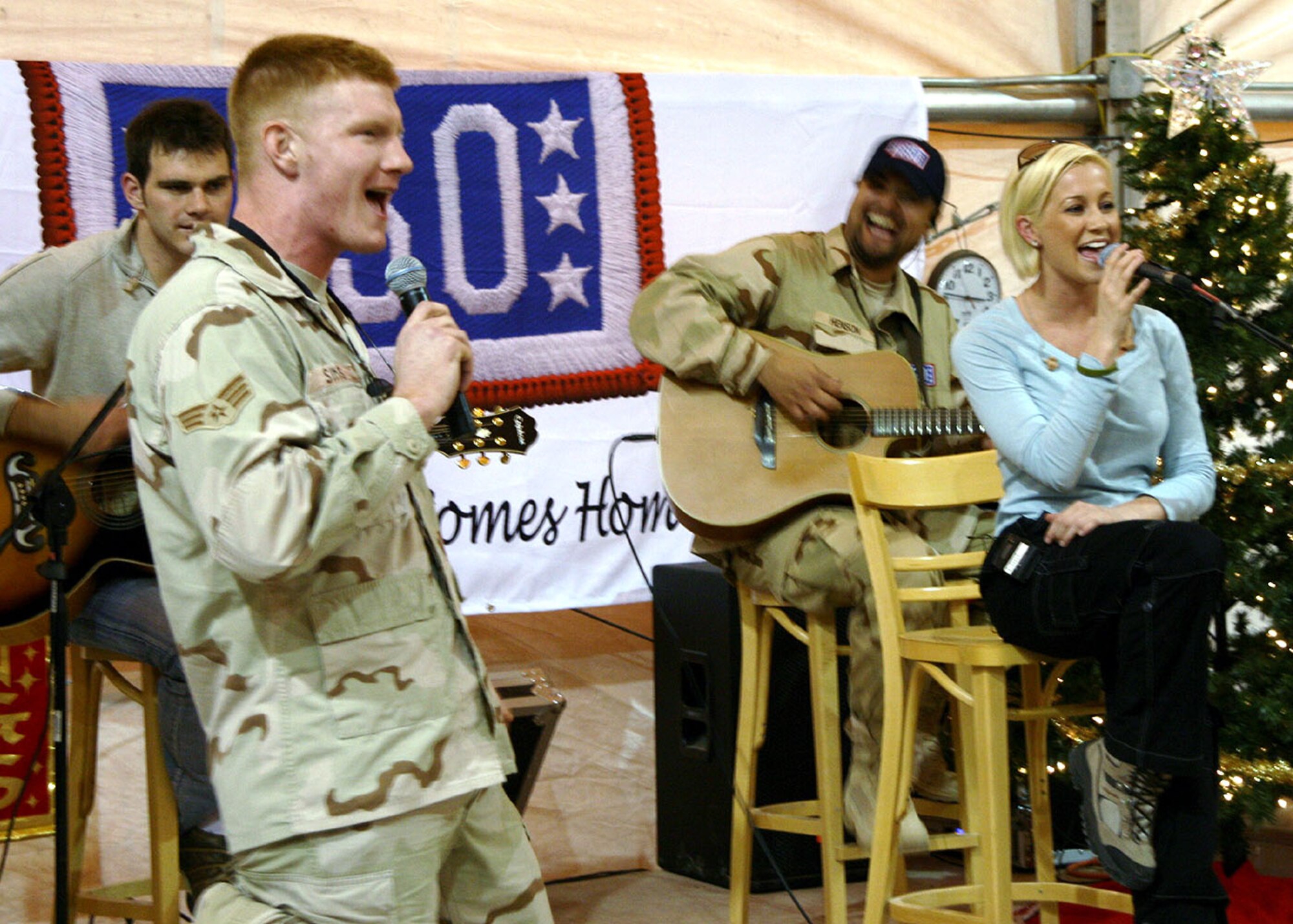 SATHER AIR BASE, Iraq -- Senior Airman Juston Sims, 447th Expeditionary Operations Support Squadron Transient Alert technician, sings with pop country music singer and songwriter Kellie Pickler during a USO-sponsored performance here Dec. 6. Airmen and Soldiers deployed here filled the base recreation center for the entertainment and the opportunity to meet Ms. Pickler, an American Idol finalist. (Master Sgt. John Lackey)
