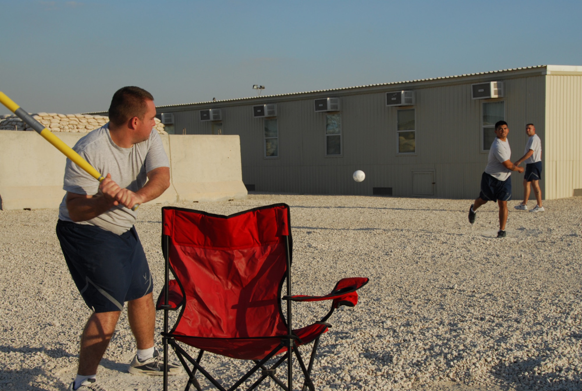 SOUTHWEST ASIA - Airmen from the 379th Expeditionary Aircraft Maintenance Squadron, B-1B Lancer,  gather for a game of modified stickball between shifts at a Southwest Asia air base Dec. 13. Staff Sgt. Philip Kinsley pitches to Staff Sgt. Steven Merida while Tech. Sgt. Jonathon Smith stands ready in the outfield. (U. S. Air Force photo/Staff Sgt. Douglas Olsen)