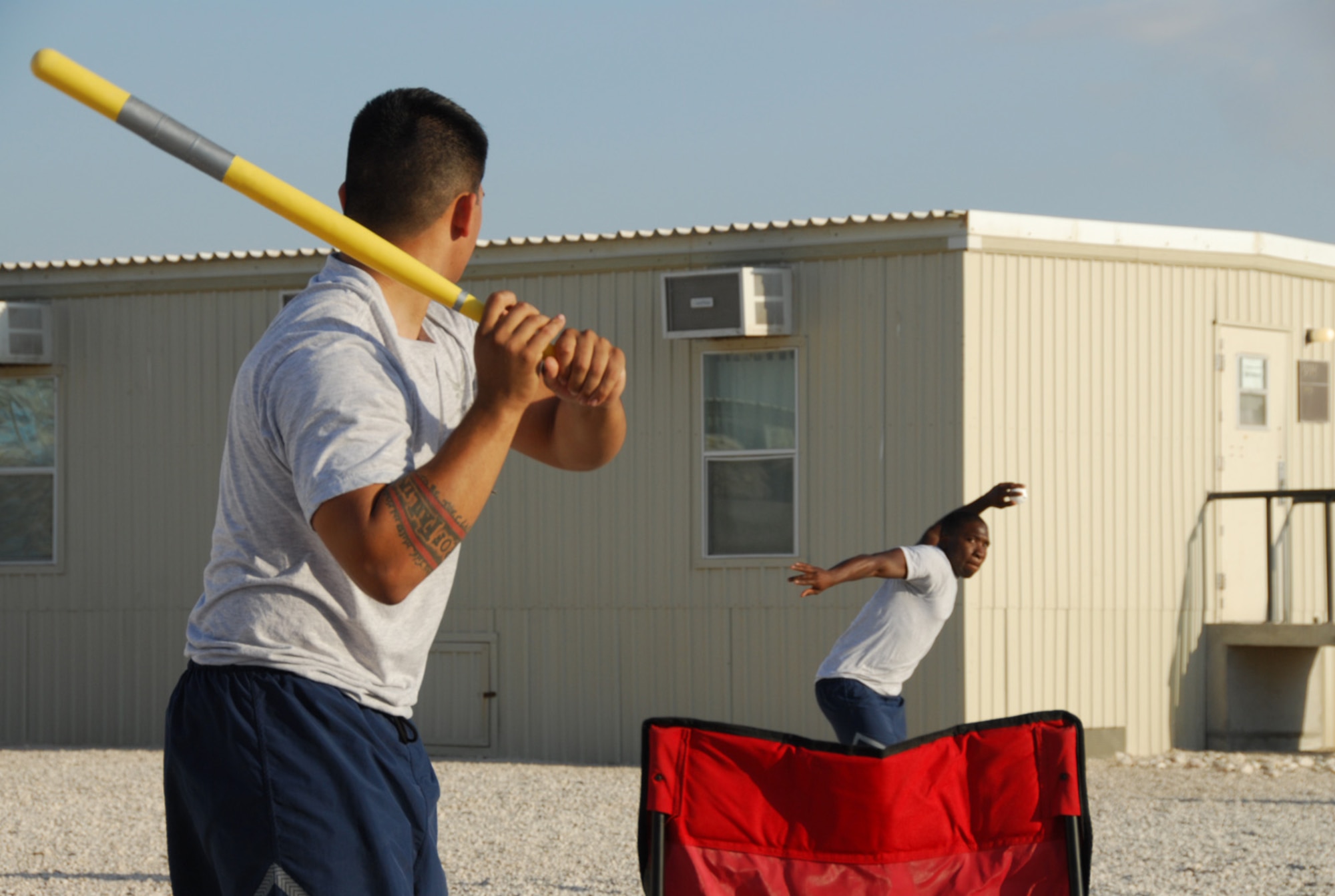 SOUTHWEST ASIA - Airmen from the 379th Expeditionary Aircraft Maintenance Squadron, B-1B Lancer, gather for a game of modified stickball between shifts at a Southwest Asia air base Dec. 13. Airman 1st Class Riyyad Schools winds up to deliver a pitch to Staff Sgt. Philip Kinsley. (U. S. Air Force photo/Staff Sgt. Douglas Olsen)