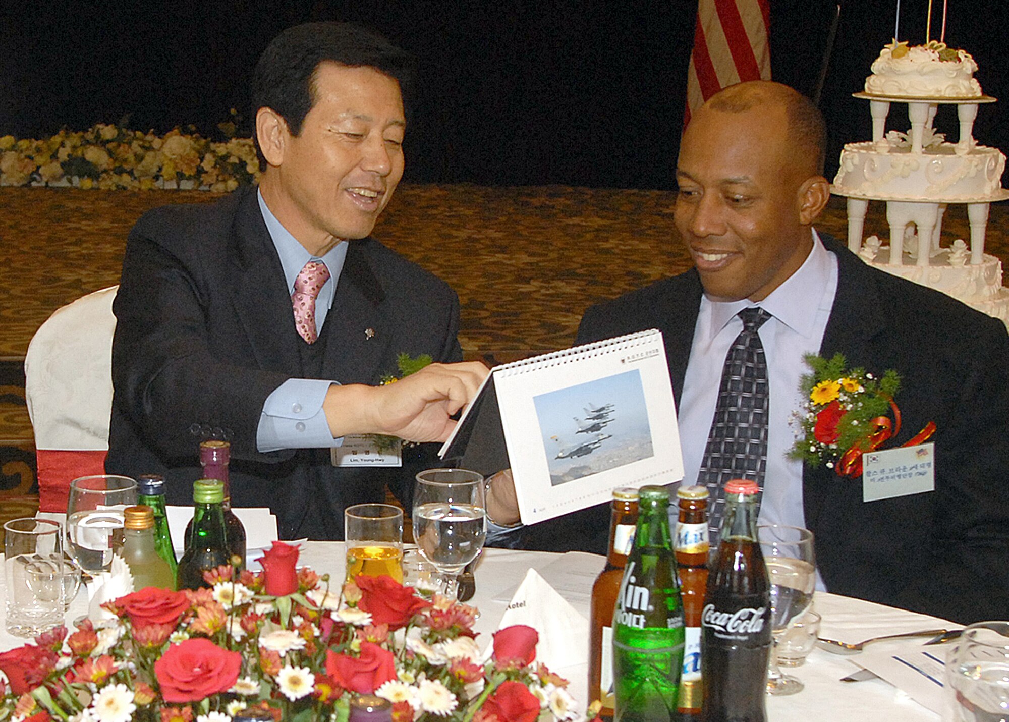 GUNSAN CITY, South Korea -- Mr. Yim, Yong Hwi, chairman of the Retired Reserve Officer Training Corps, shows Col. CQ "Wolf" Brown, 8th Fighter Wing commander the associations photo calendar for 2008 during a dinner here Dec. 13 . The Annual Friendship Dinner as part of the Good Neighbor Program highlights the relationship between the Republic of Korea and United States' military. (U.S. Air Force photo/Senior Airman Giang Nguyen)