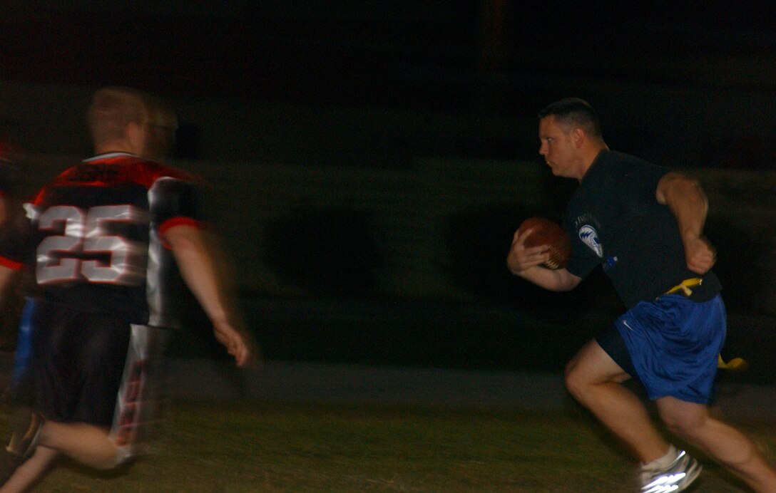 Tigers quarterback Capt. Bill “Moose” Free elects to cradle the pigskin and rush after he stepped into the collapsing pocket, pump faked to his right and still could not find an open receiver. Captain Free managed to gain a first down after this impressive run when he noticed the 36th Munitions Squadron’s secondary was spread thin across the middle of the playing field. Both teams had gifted sprinters, which had a huge impact on the game’s outcome. (Air Force photo/Tech. Sgt. Steven Wilson)