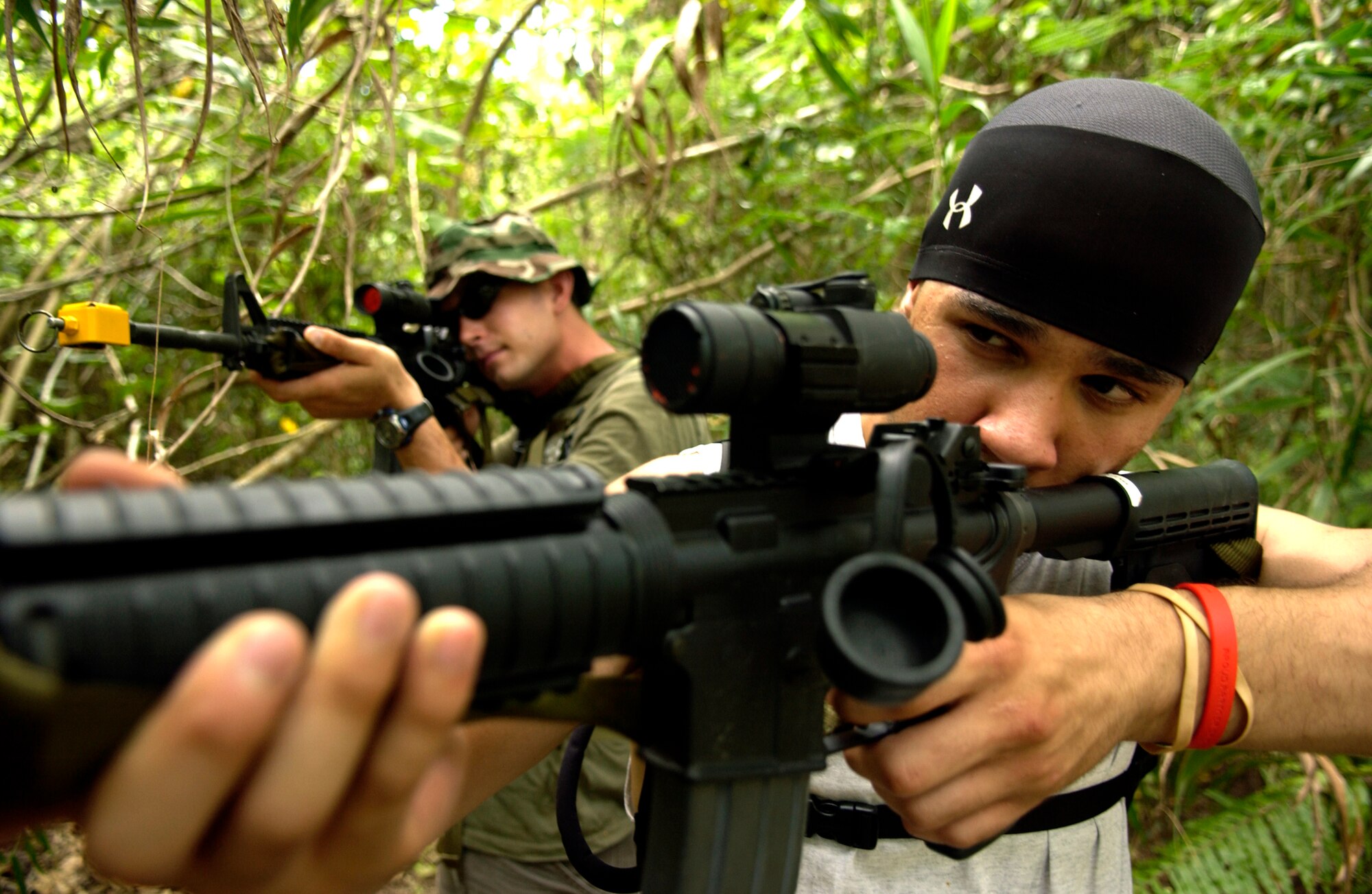 Airman 1st Class Victor DeJesus (foreground) along with Airman 1st Class James Blackwell (background), 36th Civil Engineering Squadron, shoot blanks in the jungles of Andersen South to get the attention of members of the 36th Contingency Response Group during field exercise training June 19. The week long exercise is being held to meet 36th CRG End of Quarter Performance Objectives that include mission analysis and exercising the deployment process. (U.S. Air Force photo/Senior Airman Miranda Moorer)                            