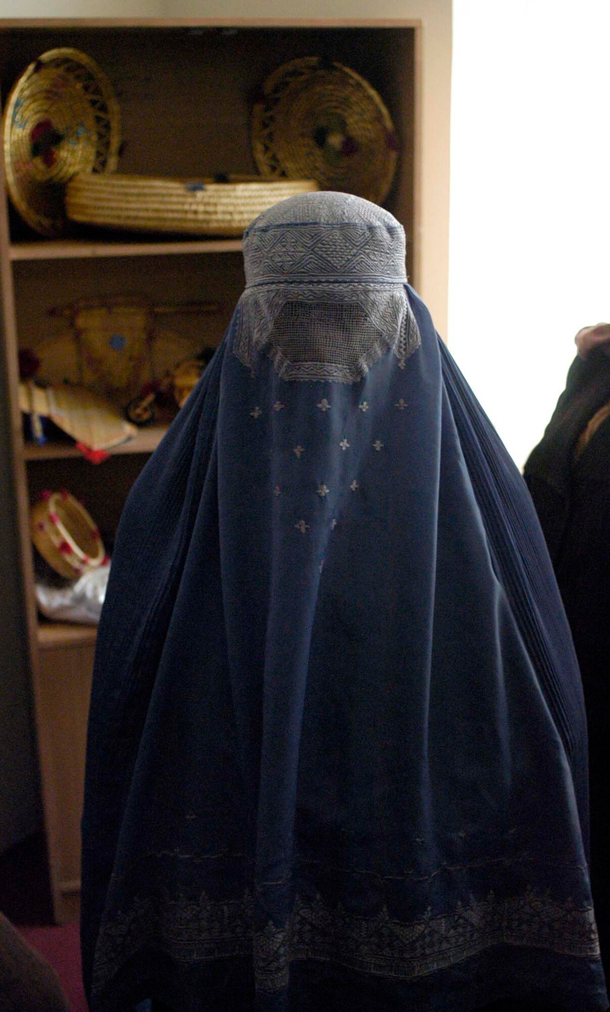 KAPISA PROVINCE, Afghanistan - An Afghan woman sells handmade crafts during the opening of a women's shelter here, Dec. 13.  The Bagram Provincial Reconstruction Team provided more than $86 thousand in support of the shelter's construction, which was accomplished by local contractors. (U.S. Air Force Photo by Staff Sgt. Mike Andriacco)