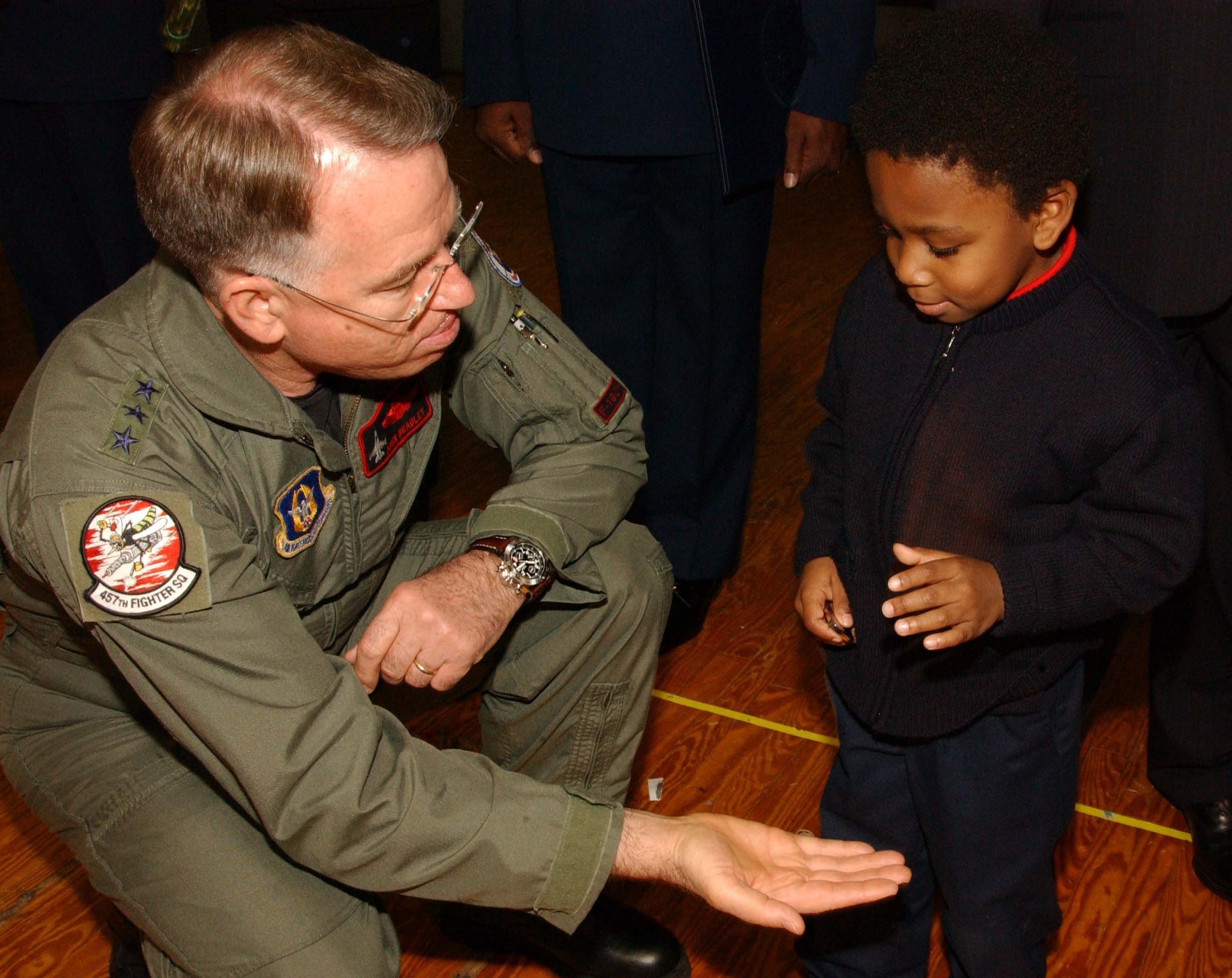ANDREWS AIR FORCE BASE, Md. -- Lt. Gen. John A. Bradley, commander of Air Force Reserve Command, gives a coin to the son of 459th Aeromedical Staging Squadron retiree Tech. Sgt. Gail Holley, in exchange for a playful "gimme five" at the 459th Air Refueling Wing commander's call Dec. 8. General Bradley attended the call to recognize star performers, chat with Airmen and discuss topics relevant to the AFRC. (U.S. Air Force photo/Staff Sgt. Amaani Lyle)