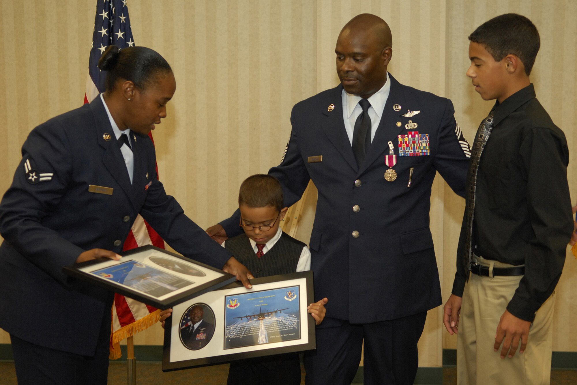 Airman 1st Class Stacy Jeffrey presents Tyrell and Marston Henry gifts on the behalf of former Command Chief Master Sergeant Henry Morgan during his retirement ceremony here Dec. 14. Chief Morgan served 30 years in the United States Air Force. (U.S. Air Force photo by Senior Airman Elizabeth Rissmiller)