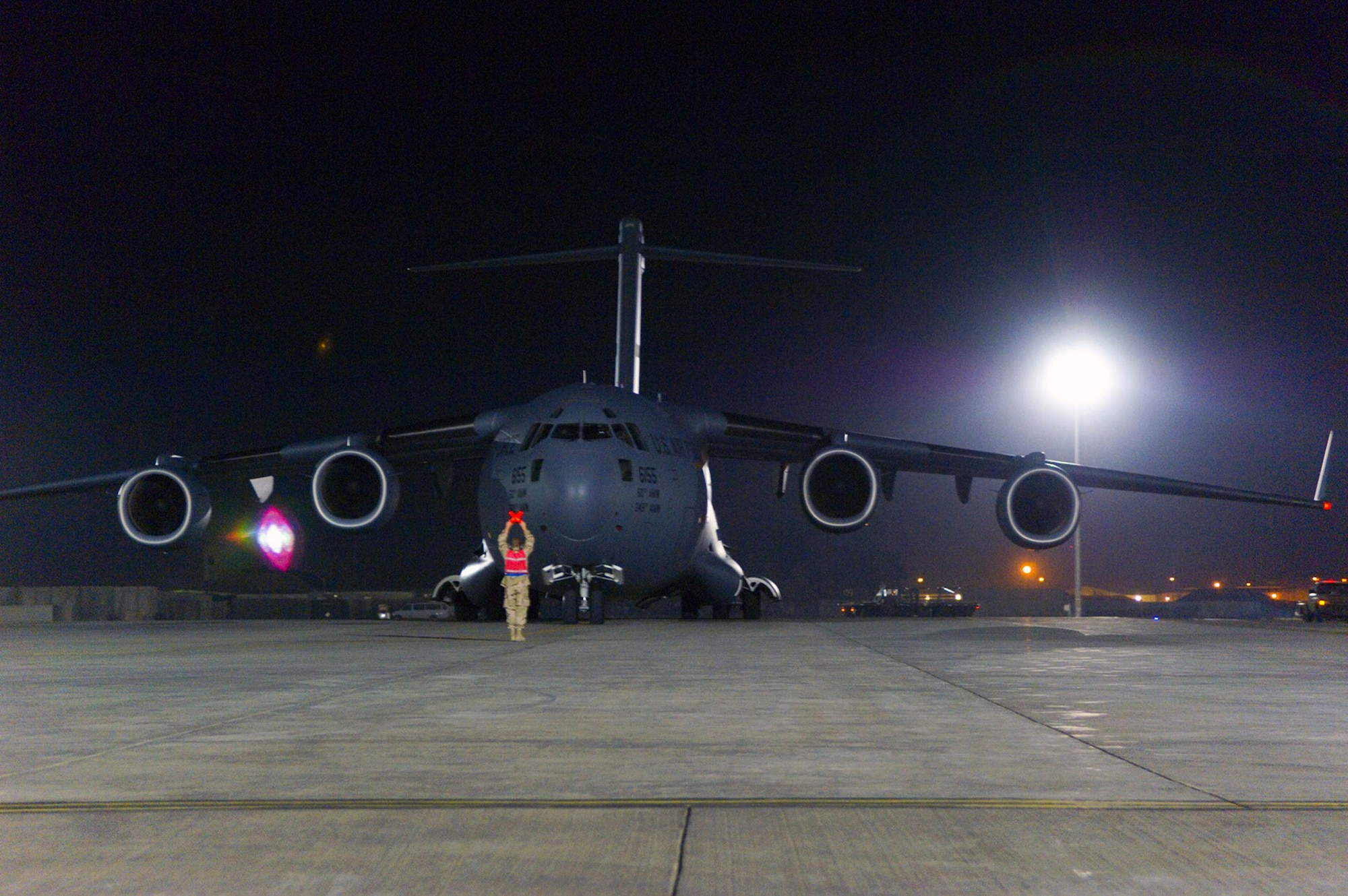 A crew chief marshals in a C-17 Globemaster III for download on the flightline Dec. 8 at Balad Air Base, Iraq. The C-17 crew was delivering three new mine resistant ambush protected vehicle for the Army. C-17 aircraft were among the airframes downloaded when aerial port team members broke the single-day cargo-movement record here Dec. 6 by moving more than 400 tons of cargo. (U.S. Air Force photo/Staff Sgt. Travis Edwards)