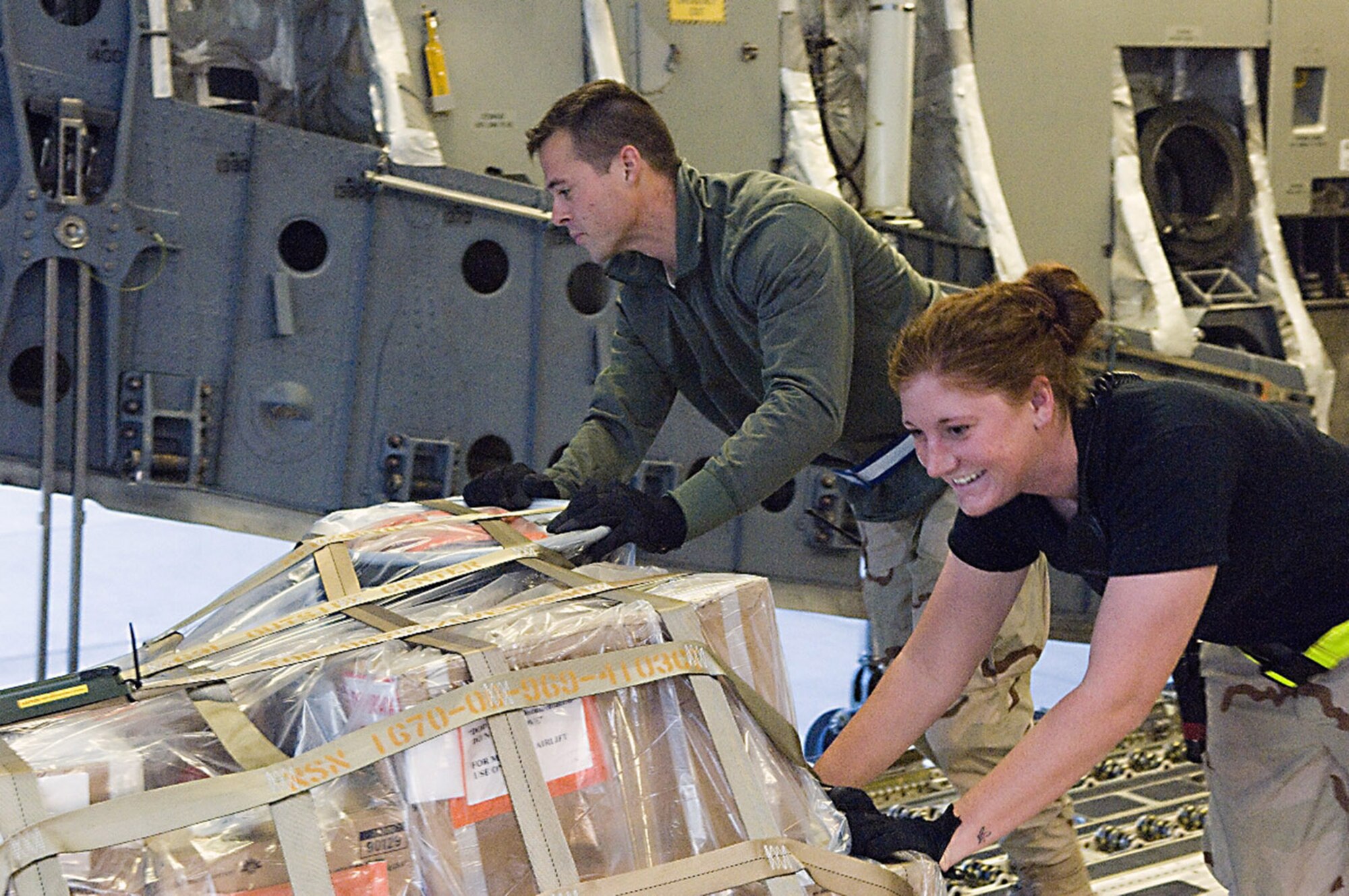 Airman 1st Class Paula Putrino and Staff Sgt. Michael Groen push a pallett onto an aircraft cargo loader Dec. 8 at Balad Air Base, Iraq. Both Airmen were part of the team who broke the single-day record for cargo movement, moving 930 tons of equipment and supplies in a day. Airman Putrino and Sergeant Groen are 332nd Expeditionary Logistics Readiness Squadron aerial porters, and are deployed from Pope Air Force Base, N.C. (U.S. Air Force photo/Staff Sgt. Travis Edwards)