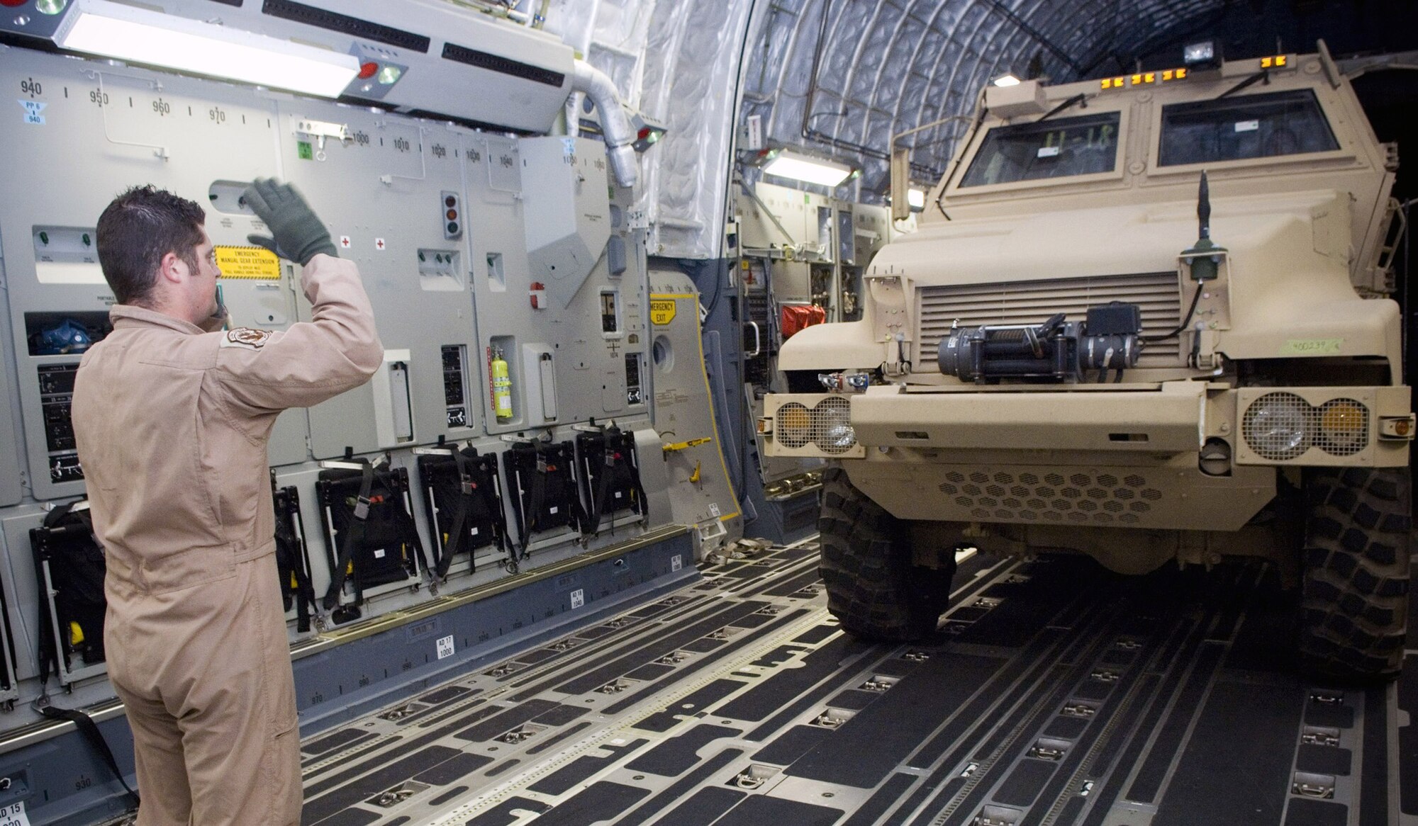 Airman 1st Class Grant Phillips marshals out a brand new mine resistant ambush protected vehicle to the flightline Dec. 8 at Balad Air Base, Iraq. Driving the MRAP is Senior Airman Christine Mirgon, a member of the aerial port team who set a new record for most cargo movement in a day Dec. 6. Airman Phillips is a C-17 Globemaster III loadmaster deployed from Charleston Air Force Base, S.C., and Airman Mirgon is a 332nd Expeditionary Logistics Readiness Squadron aerial porter deployed from Offut Air Force Base, Neb. (U.S. Air Force photo/Staff Sgt. Travis Edwards)