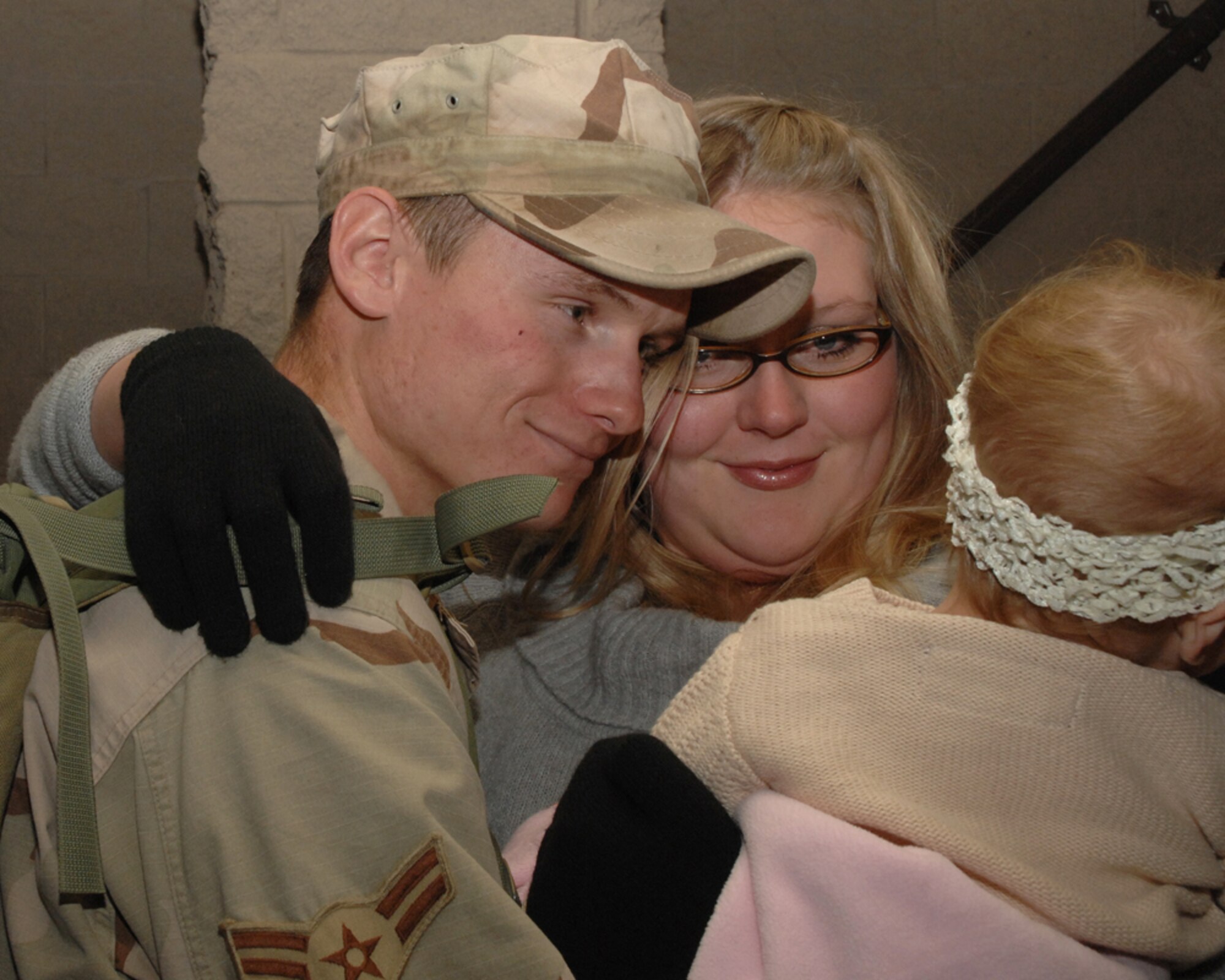 Airman 1st Class David Adams, 49th Security Forces Squadron, is welcomed home by his wife, Nicole, and daughter, Lilly, Wednesday, Dec. 12, 2007, at Holloman Air Force Base, N.M. Airman 1st Class Adams was one of the 25 Airmen returning from the deployment to Camp Bucca, Iraq. (U.S. Air Force photo/Airman 1st Class Tiffany Trojca)