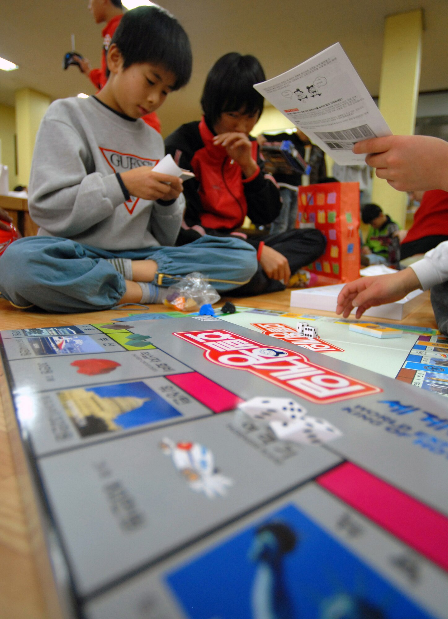 Children from the Kae Jong orphanage play a Korean version of Monopoly here Dec. 15 in Kae Jong, South Korea. Airmen from Kunsan Air Base, South Korea, spent the afternoon handing out gifts, coloring, eating, and playing with the children. The Airmen donated various gifts to include beanie babies and a PlayStation 2. (U.S. Air Force photo/Senior Airman Steven R. Doty) 
