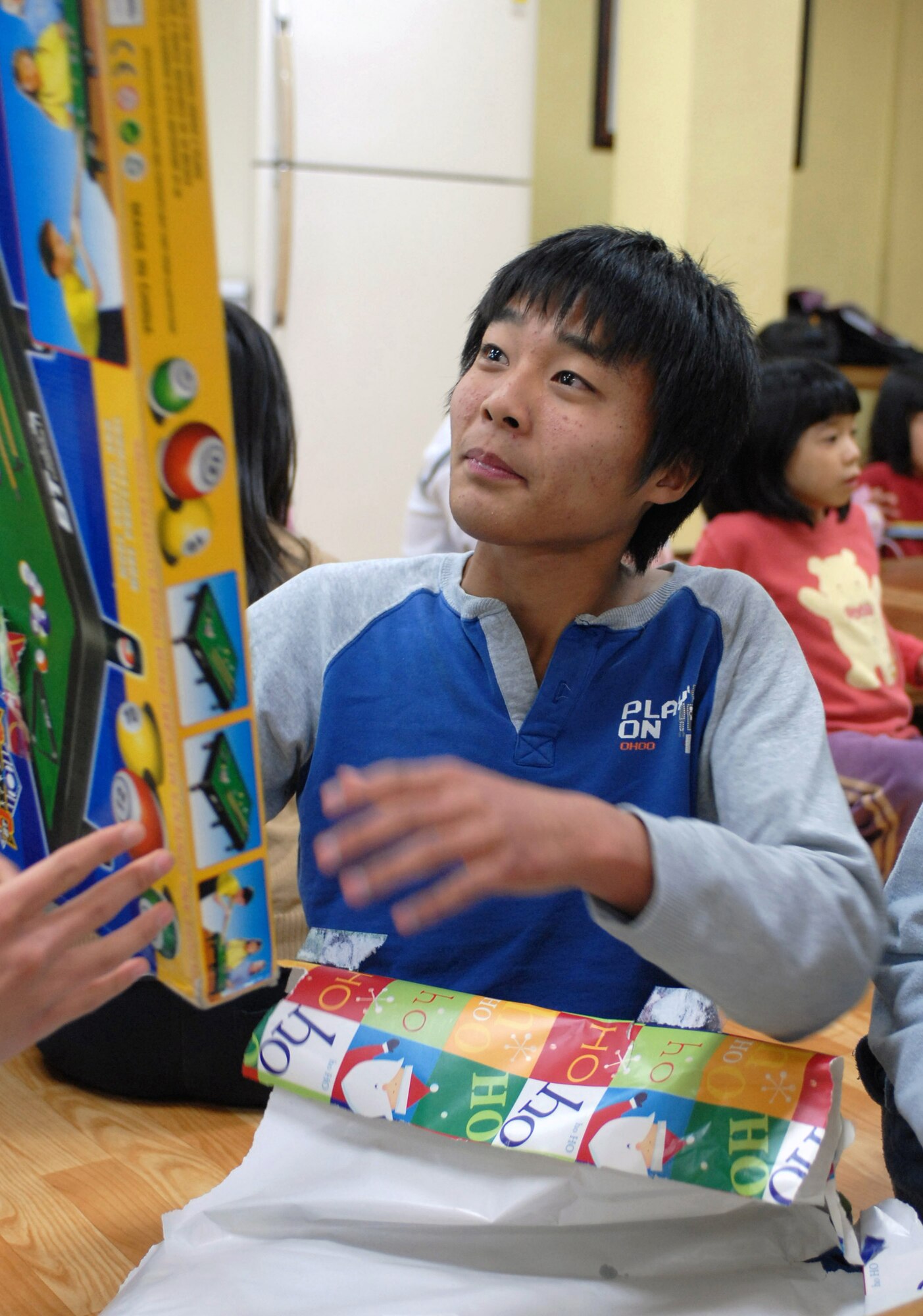 A child from the Kae Jong orphanage opens a gift during an Airmen Committed to Excellence Christmas Party Dec. 15 in Kae Jong, South Korea. Airmen from Kunsan Air Base, South Korea, spent the afternoon handing out gifts, coloring, eating, and playing with children during the visit. The Airmen donated various gifts to include beanie babies and a PlayStation 2. (U.S. Air Force photo/Senior Airman Steven R. Doty) 
