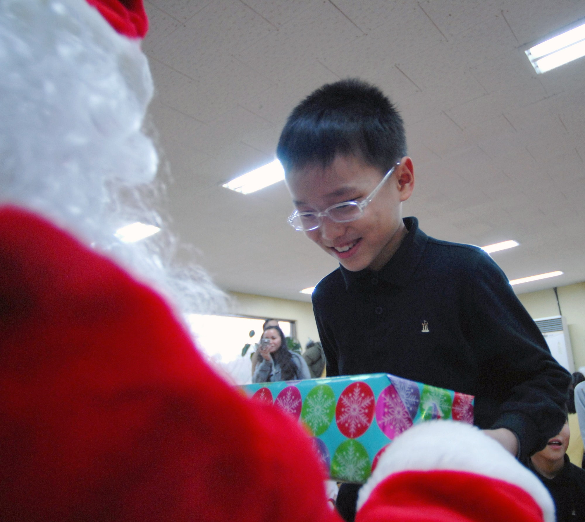 Santa, played by Tech. Sgt. John Craven, hands out a gift to a Kae Jong orphan Dec. 15 in Kae Jong, South Korea. Airmen from Kunsan Air Base, South Korea, spent the afternoon handing out gifts, coloring, eating, and playing with children during an Airmen Committed to Excellence-sponsored trip. The Airmen donated various gifts to include beanie babies and a PlayStation 2. (U.S. Air Force photo/Senior Airman Steven R. Doty) 

