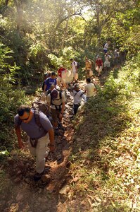 COMAYAGUA, Honduras -- Servicemembers assigned to Joint Task Force-Bravo cross a stream en route to the village of Capiro to deliver approximately 600 pounds of food Dec. 14.  The three-mile hike, sponsored by the JTF-Bravo chapel, was the fourth in a series of five scheduled trips.  (U.S. Air Force photo by Staff Sgt. Austin M. May)
