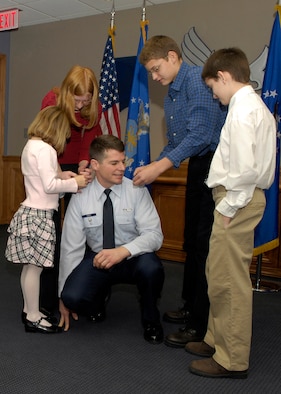 HANSCOM AFB, Mass. -- Col. Russell Kurtz, Deputy Director of Engineering, kneels while his children (from left) Katie, 7,  Ashley,14, Nicholas, 14, and Tyler,11, help pin on his new rank during his promotion ceremony Dec. 3. (U.S. Air Force photo by Mark Wyatt.)
