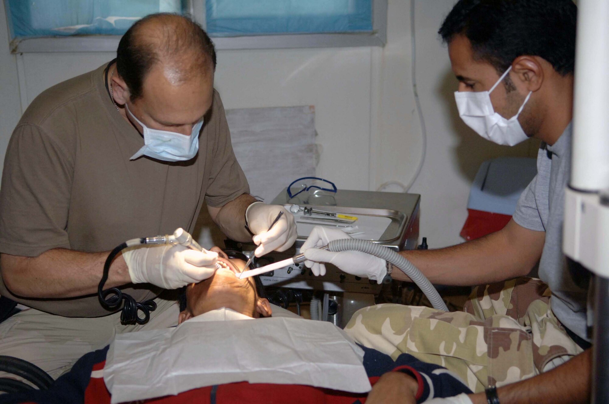Lt. Col. Robert Beck performs a root canal with the assistance of an Iraqi dental technician Dec. 5 at Victory Base Complex, Iraq. The Iraqi soldiers work side by side with the Airmen during procedures to get hands on experience and guidance as they prepare to take over the clinic. Colonel Beck, a Special Operations Iraqi Transition Team dental adviser, is deployed from Offutt Air Force Base, Neb. (U.S. Air Force photo/Senior Airman Terri Barriere) 
