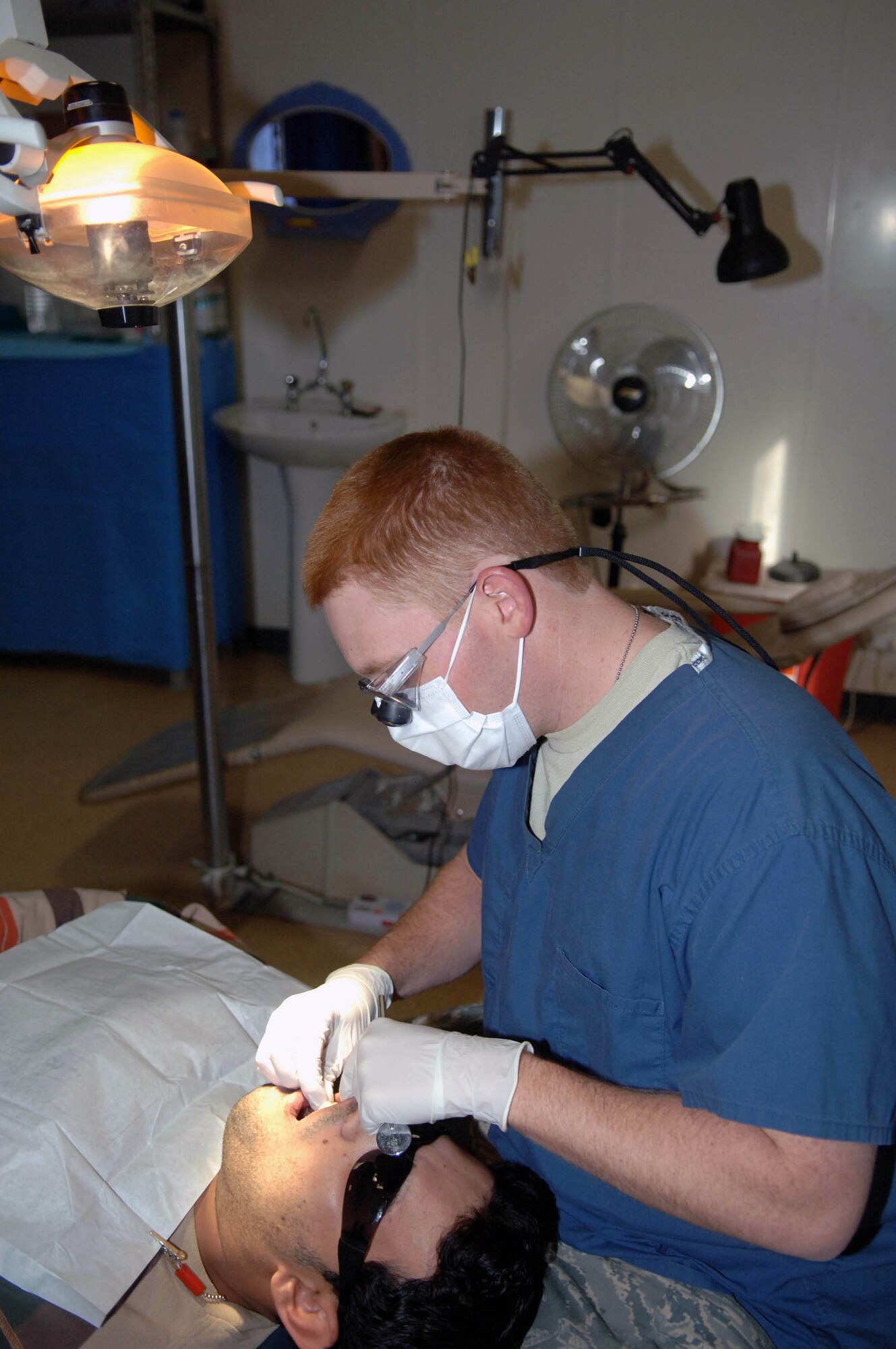 Capt. Lanny Giesler packs a patients mouth with gauze after performing a root canal Dec. 5 at Victory Base Complex, Iraq. The clinic sees an average of 12 to 16 patients a day. Captain Giesler, a Special Operations Iraqi Transition Team dental adviser, is deployed from Little Rock Air Force Base, Ark. (U.S. Air Force photo/Senior Airman Terri Barriere) 

