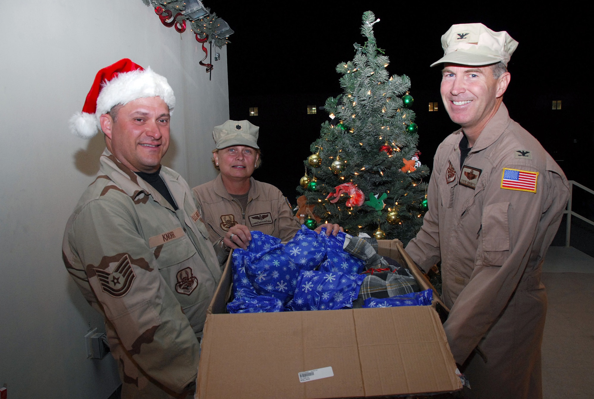 SOUTHWEST ASIA - Tech. Sgt. Eric Knorr, USCENTAF Band, Hot Brass, band leader, accepts a box of candy and toys from Col. Steven Arquiette, Combined Air Operations Center, and Lt. Col. Lenora Cook, Dec. 15 at Southwest Asia air base. Sergeant Knorr and the other band members will distribute to children and troops throughout the Southwest Asia theater as the band tours the theater. The box is part of 500 pounds of candy and toys that was sent from people at Travis AFB, Calif., as part of Operation Candy Drop. Both colonels are deployed from Travis AFB, Calif. The band members of Hot Brass are deployed from Wright Patterson AFB, Ohio. (U. S. Air Force photo/Staff Sgt. Douglas Olsen)