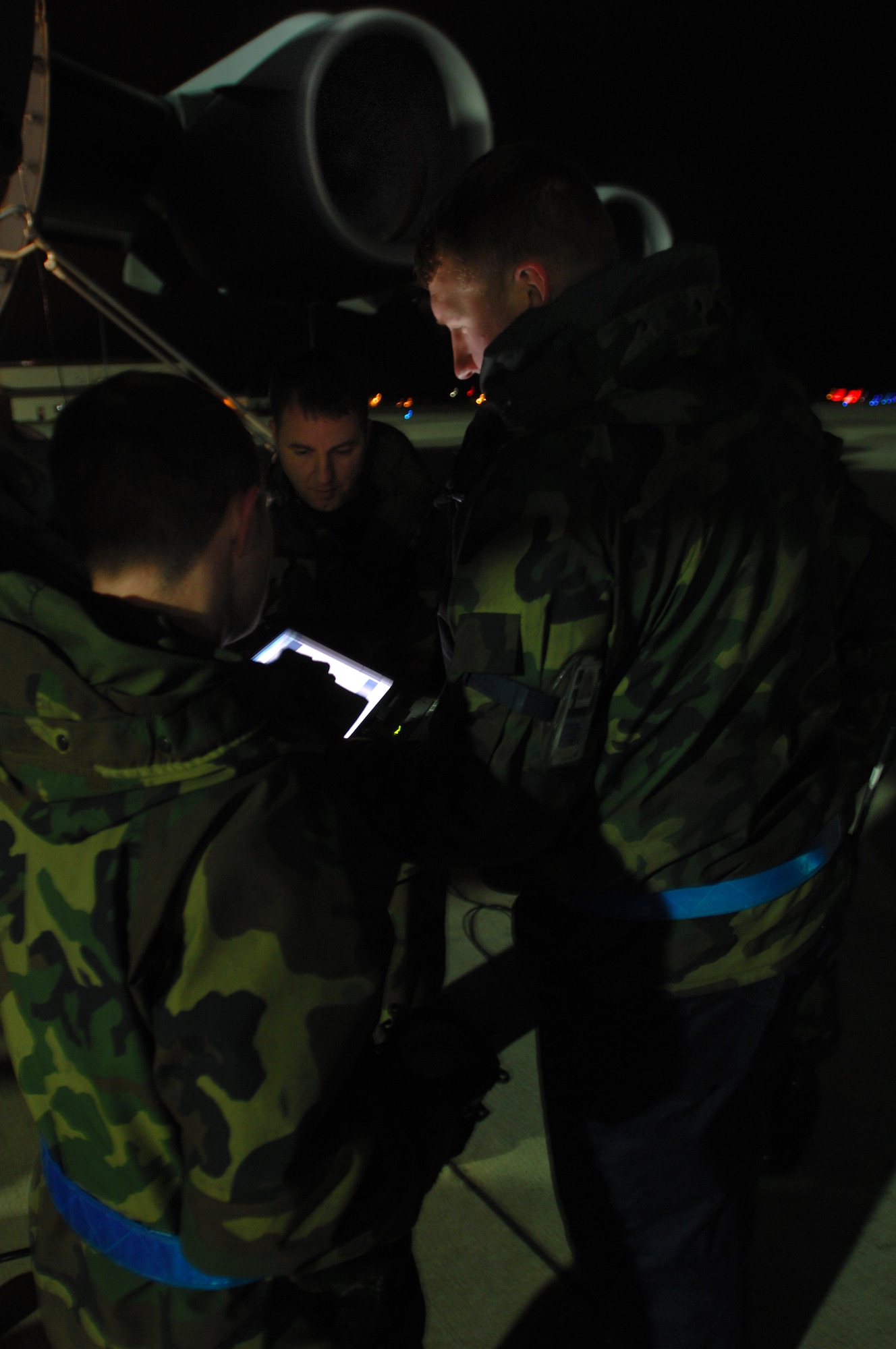 Staff Sgt. David Preston, 723rd Air Mobility Squadron (right), reviews a technical orders manual on a laptop after putting two new front tires on a C-17 Globemaster III as part of a quick turn mission Dec 13. Night time operations are a large portion of the Ramstein flying mission. (U.S. Air Force photo/Airman 1st Class Kenny Holston)