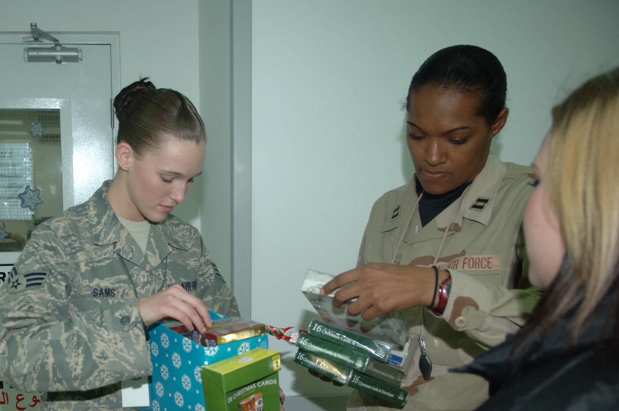 BALAD AIR BASE, Iraq -- Senior Airman Amber Sams, a 332nd Expeditionary Services Squadron recreation coordinator deployed from Langley Air Force Base, Va., and Frances Gonzalez, Cards for Troops volunteer, pass out holiday cards to Capt. Colleen Lamp and Tech. Sgt. John Lafauci, both from the 332nd Expeditionary Medical Operations Squadron intermediate care ward here. Captain Colleen Lamp and Sergeant Lafauci are deployed from Lackland Air Force Base, Texas.(U.S. Air Force photo/Senior Airman Terri Barriere)