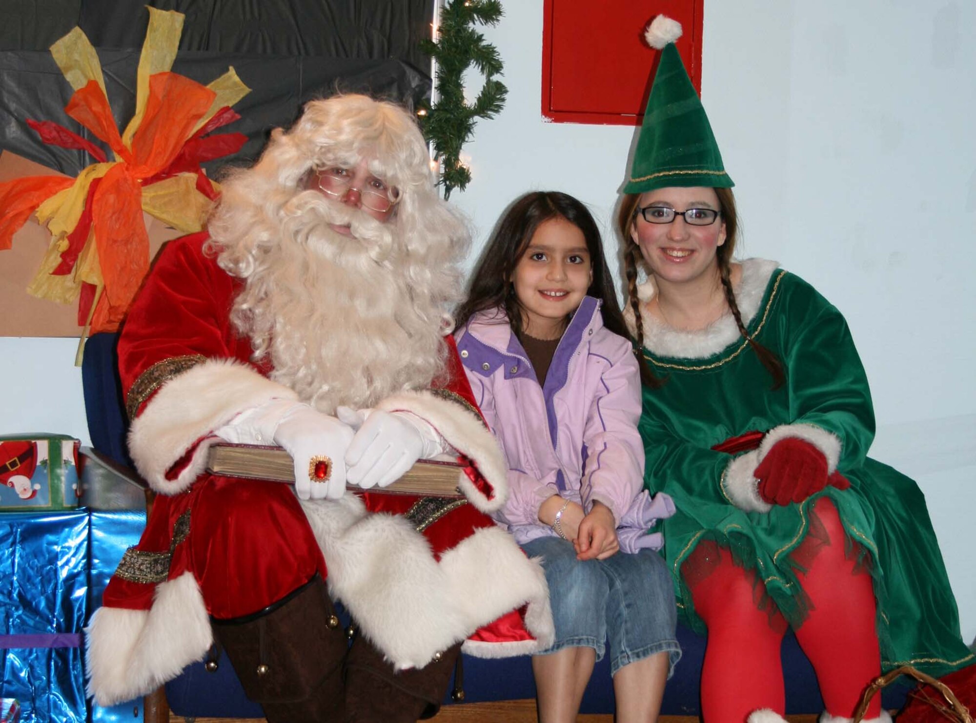 SPANGDAHLEM AIR BASE, Germany -- Allie Wyatt, daughter of Maj. Michael Wyatt, 52nd Services Squadron commander, talks with Santa Claus and head elf Jenifer Calhoun at the Spangdahlem Youth Center’s Children’s Christmas Party Dec. 15, 2007. Allie asked Santa Claus for a dog for Christmas. (Photo by Biggi Piper)