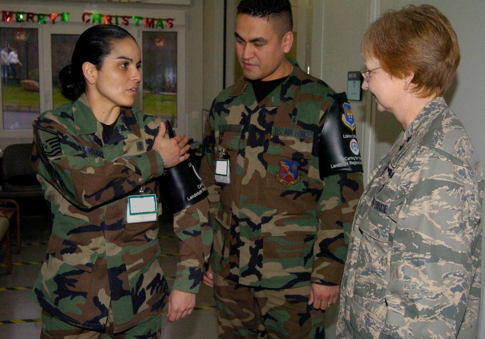Master Sgt. Melissa Rodriguez (left) displays her brassard to Maj. Gen. Melissa Rank at Landstuhl Regional Medical Center. Sergeant Rodriguez and Tech. Sgt. Jose Solis (center) wear the distinctive black arm bands to identify them as liaison officers who assist wounded servicemembers from Operations Enduring Freedom and Iraqi Freedom with administrative patient needs during their stay at LRMC. General Rank is the Assistant Air Force Surgeon General for Nursing Services and Medical Force Development. (U.S. Army Photo/Chuck Roberts)
